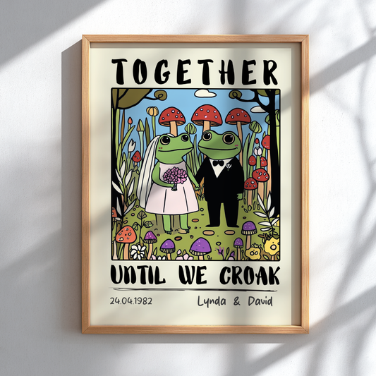 Framed artwork of two frogs in wedding attire with text 'Together until we croak' on a white wall.