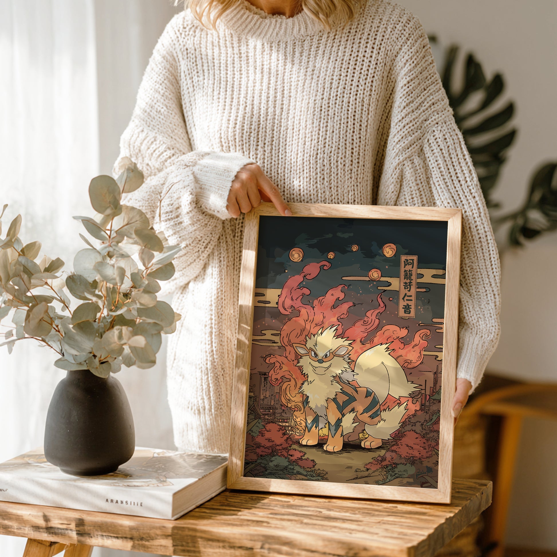 Person holding a framed artwork of Arcanine Pokemon in a home setting