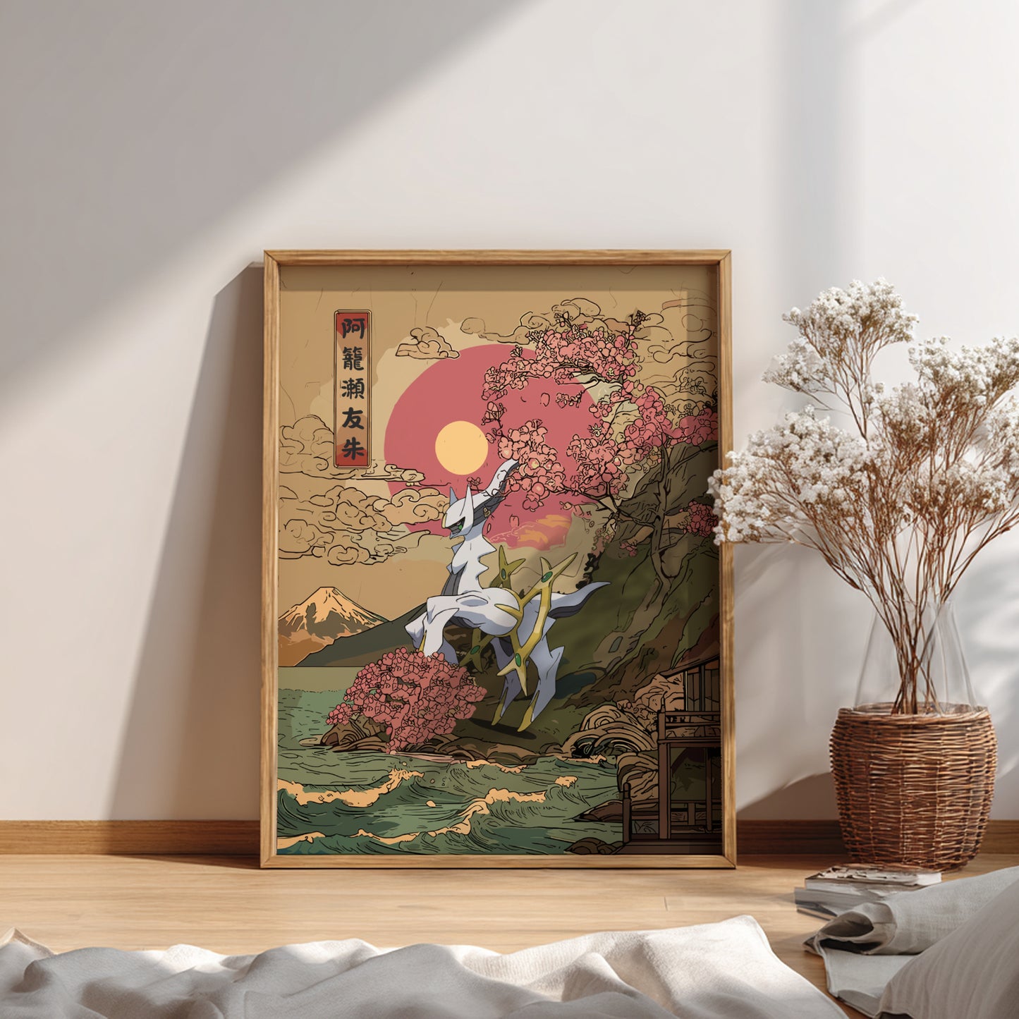 Framed artwork with a nature scene on a wall in a room with a plant and books.