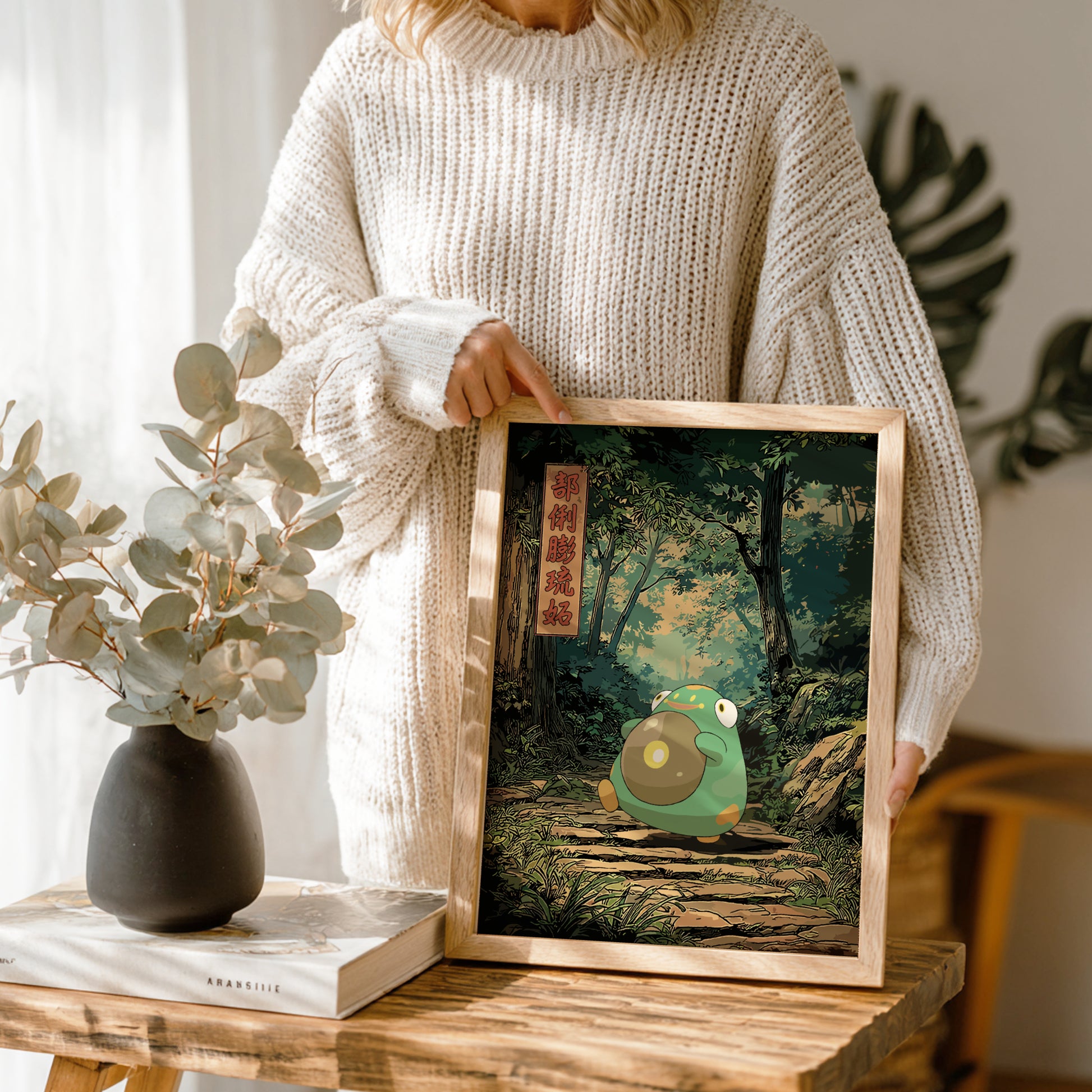 Person holding a framed illustration of Bellibolt Pokemon character in a forest setting.