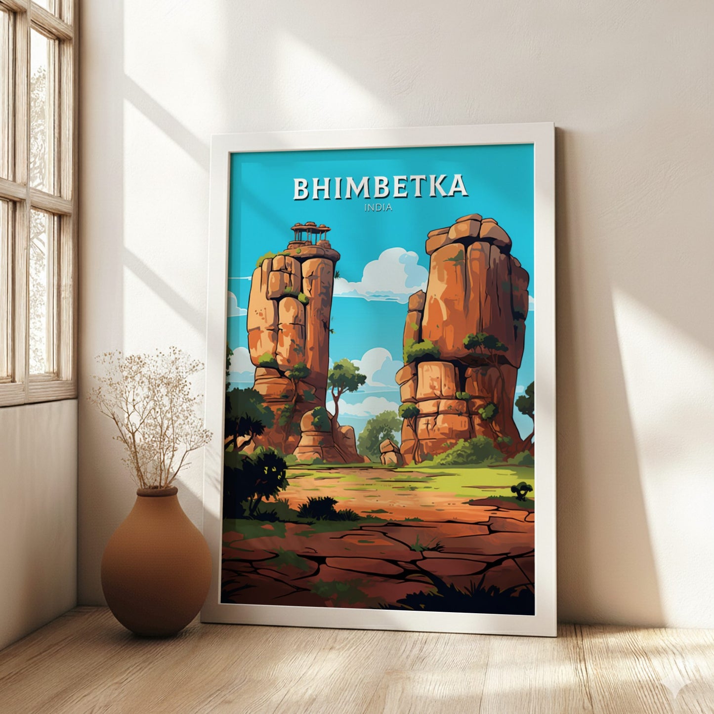 Framed poster of Bhimbetka with rocky formations and greenery in a room with a vase and window.