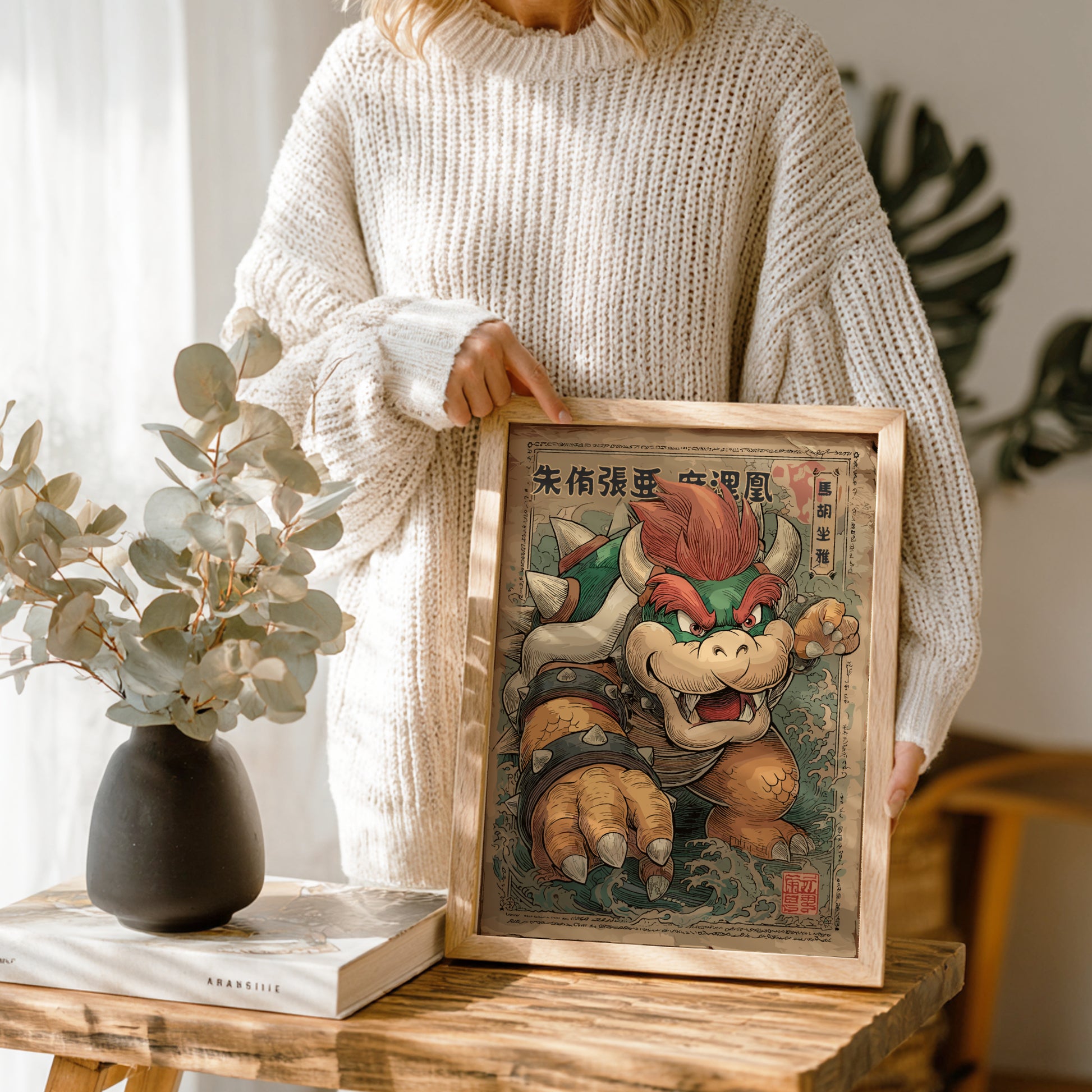 Person holding a framed artwork of King Bowser character in a home setting