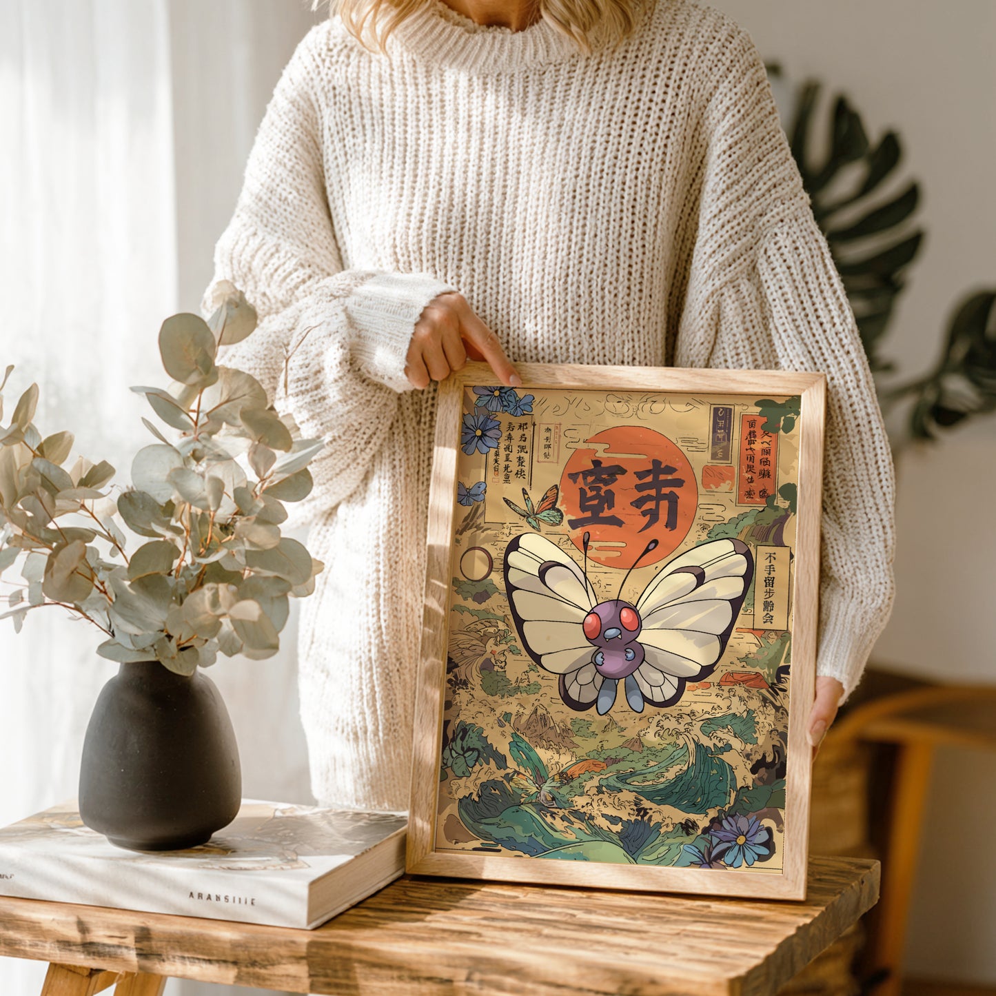 Person holding a framed artwork with Butterfree Pokemon design in a home setting