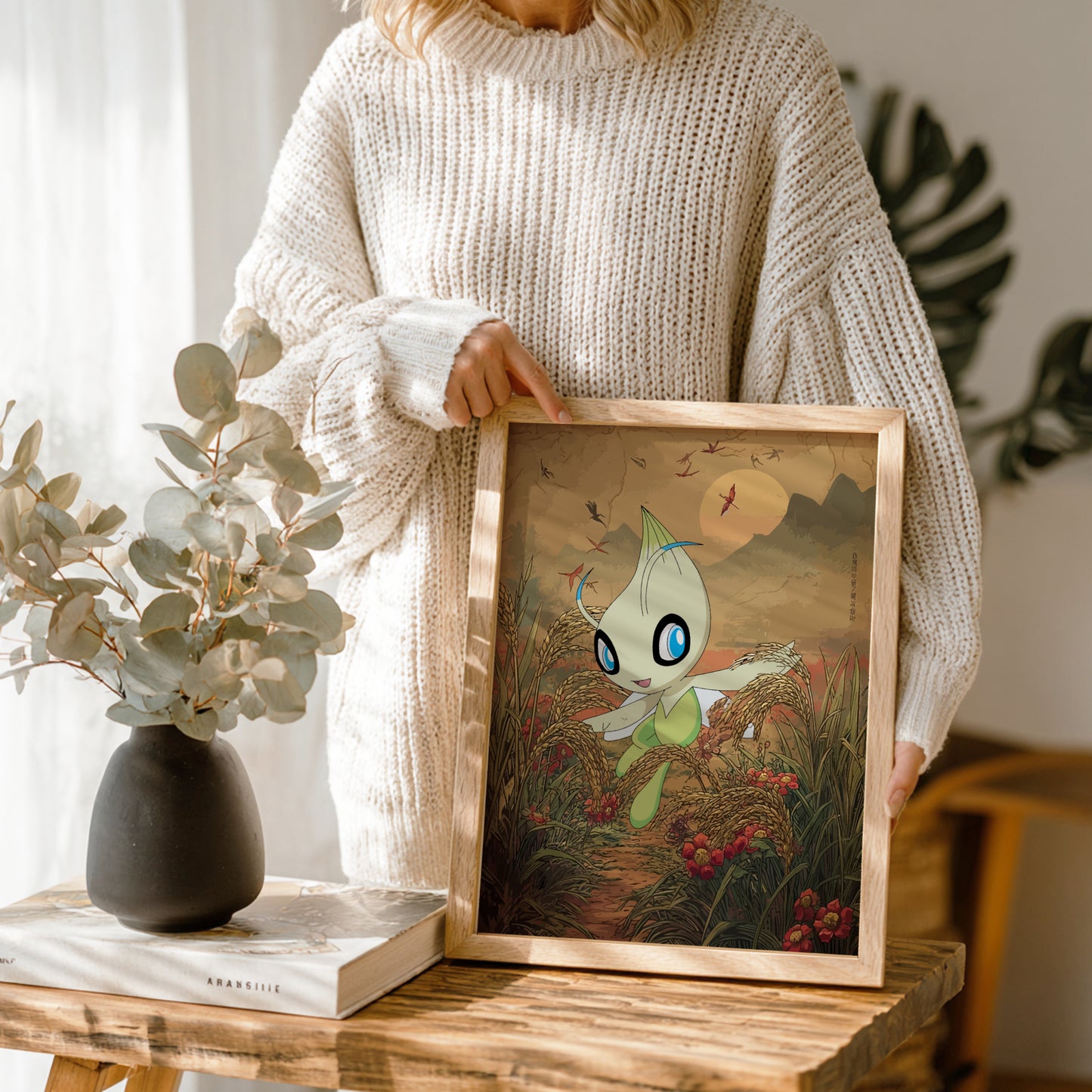 Person holding a framed artwork of Celebi Pokemon character in a natural setting