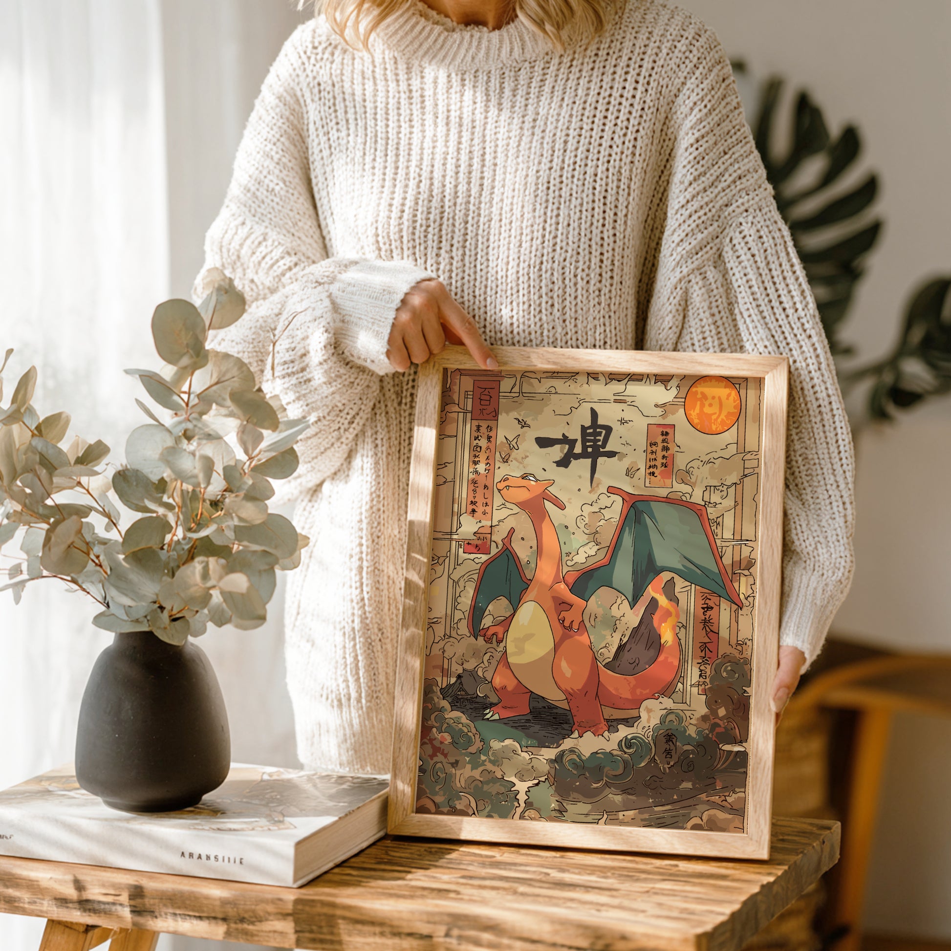 Person holding a framed artwork of Charizard Pokemon in a cozy indoor setting