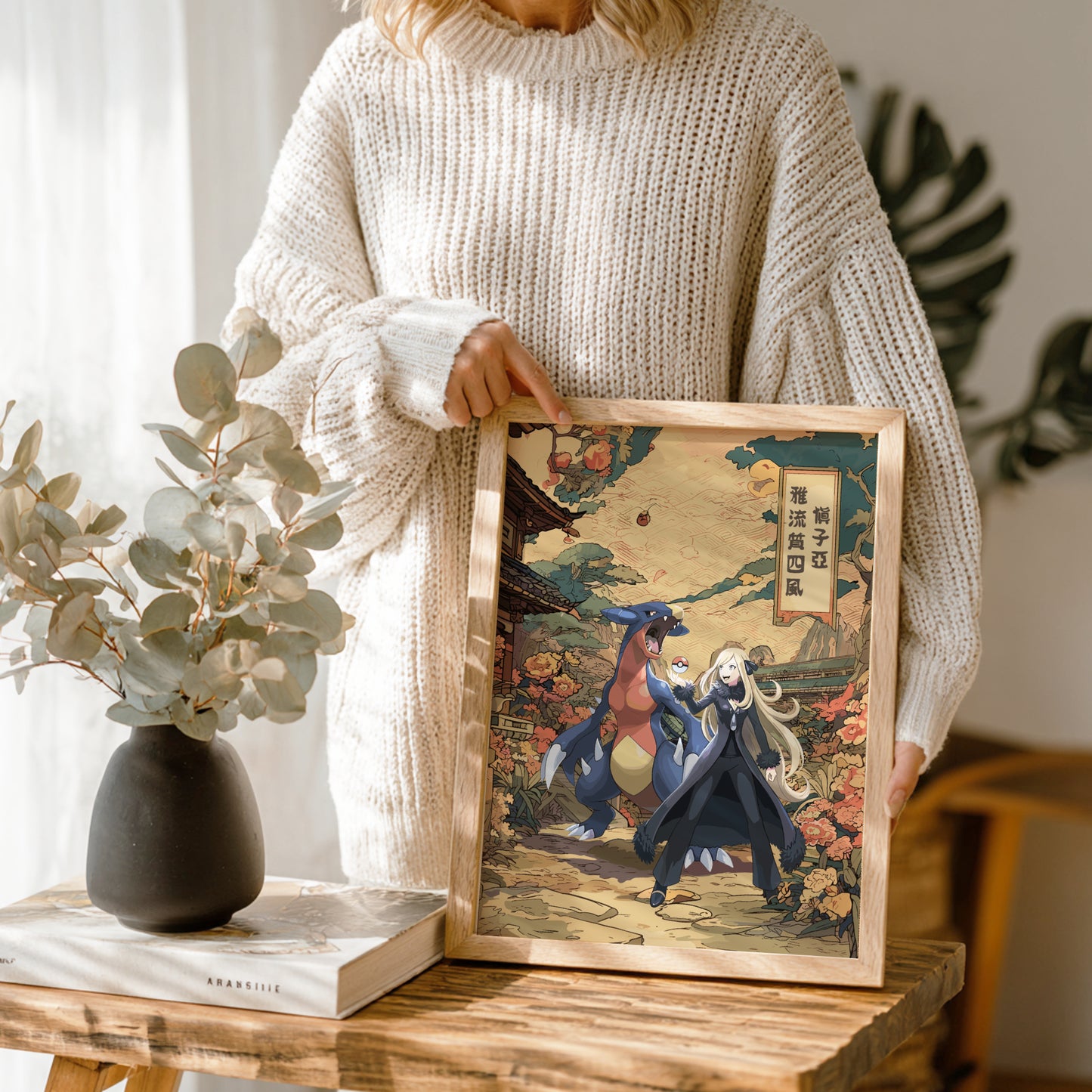 Person holding a framed artwork of Cynthia and Garchomp Pokemon in a decorative setting