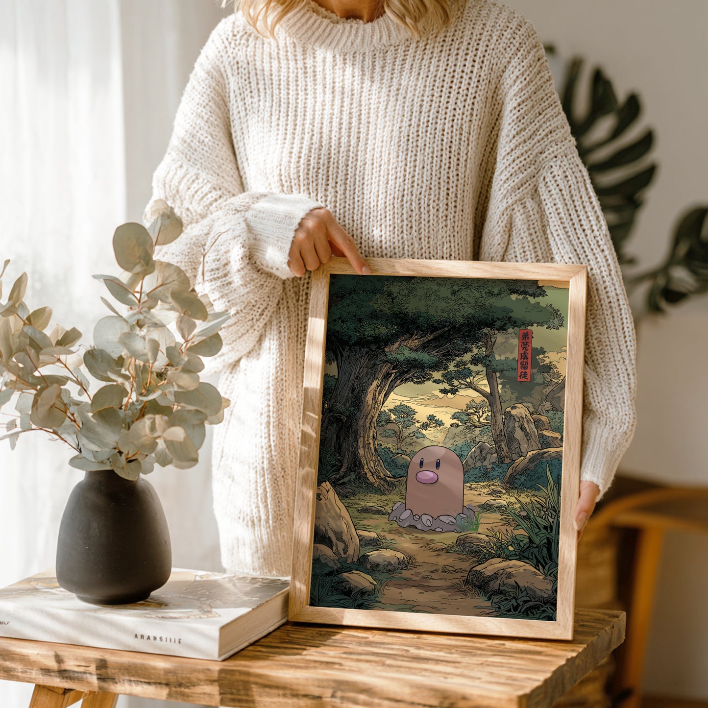 Person holding a framed artwork of Diglett Pokemon character in a forest setting.
