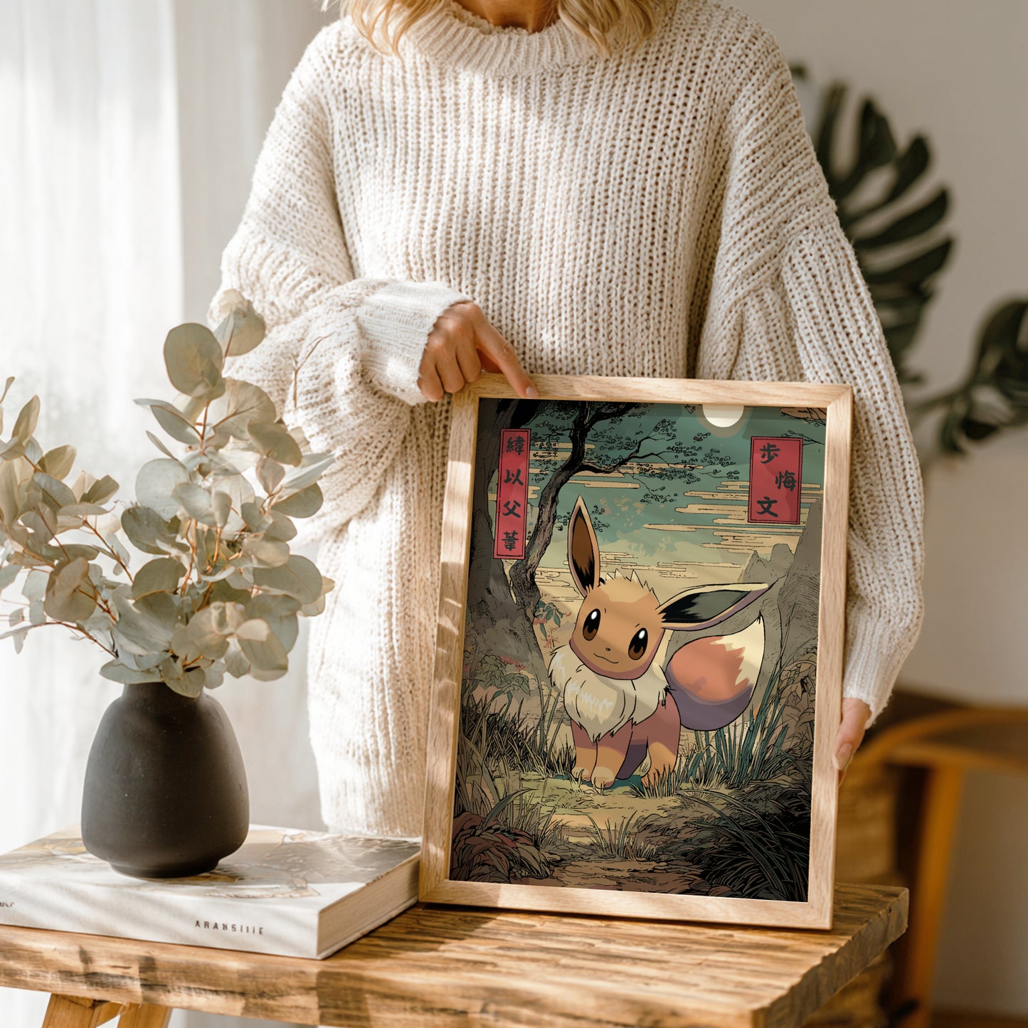 Person holding a framed artwork of Eevee Pokemon character in a natural setting