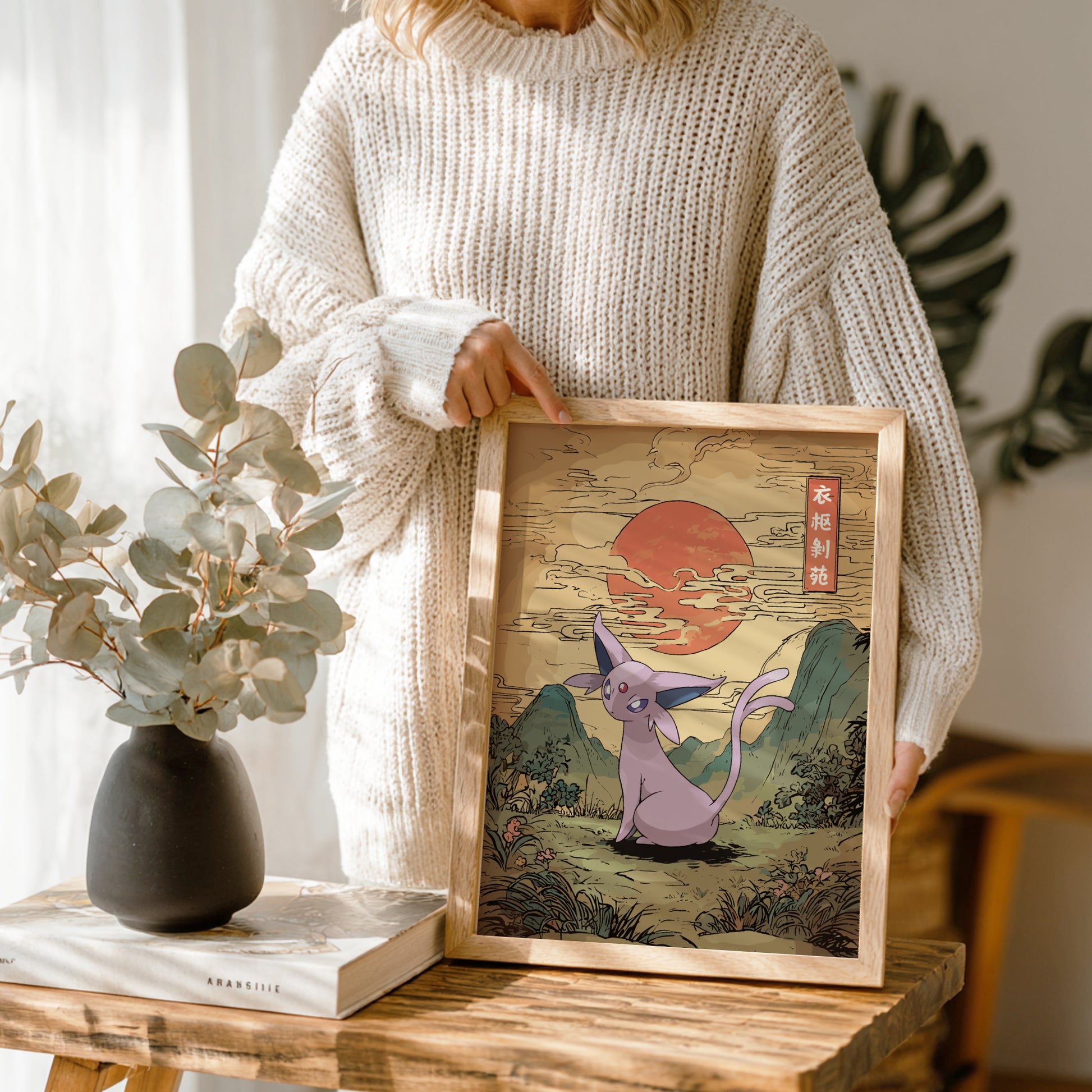 Person holding a framed artwork of Espeon Pokemon in a natural setting.