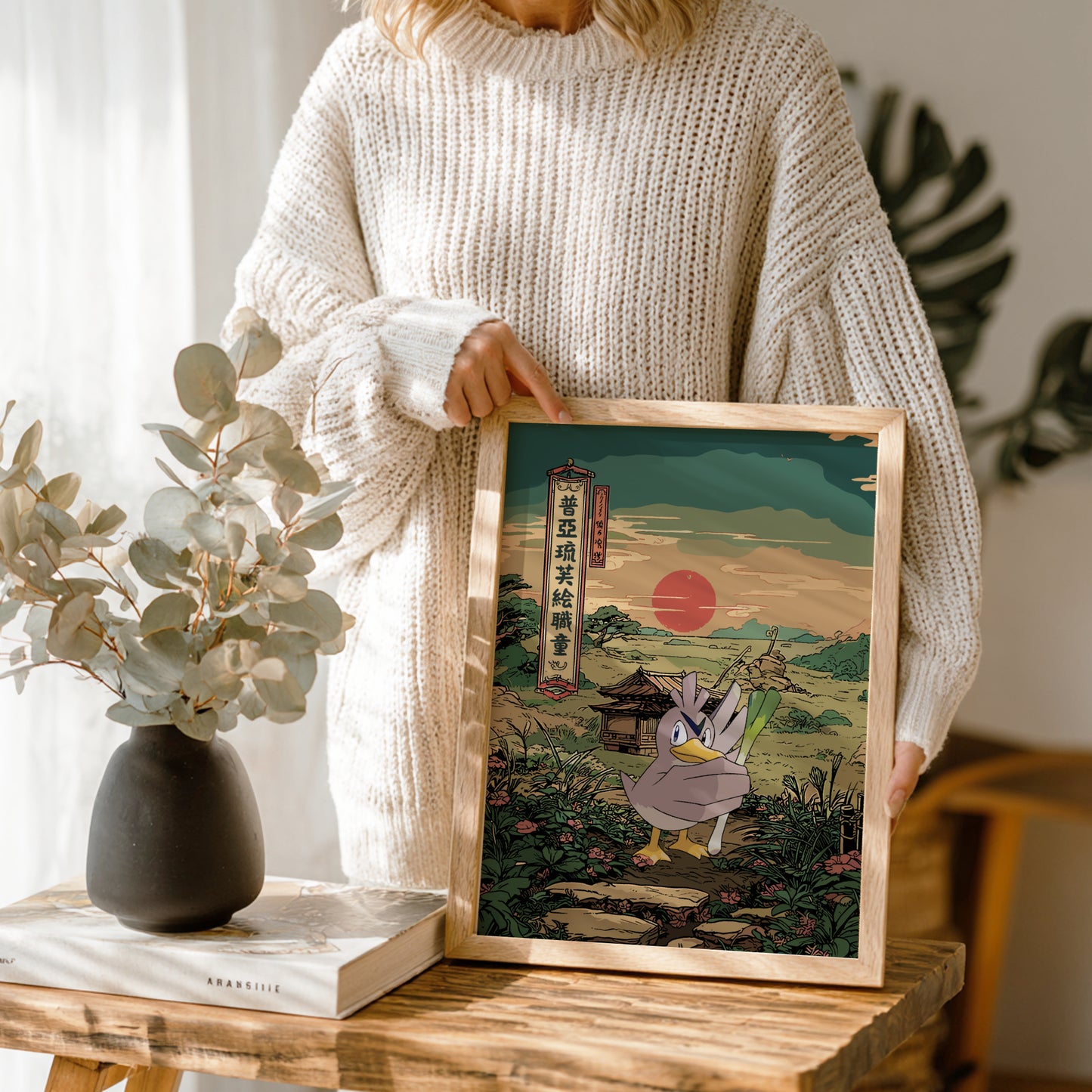 Person holding a framed artwork of Farfetch’d Pokemon character in a scenic setting