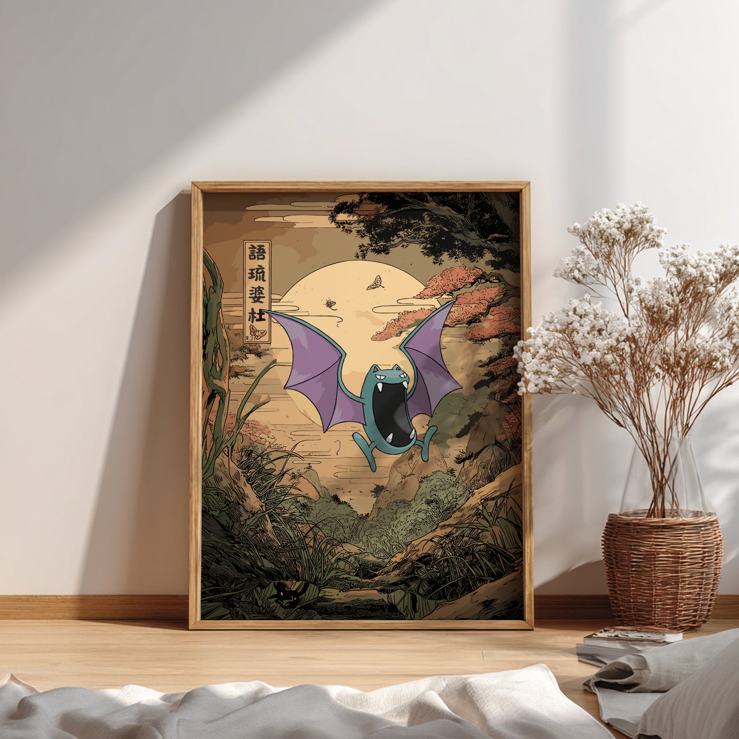 Framed artwork of Golbat Pokemon in a natural setting on a wall with a vase of dried flowers.