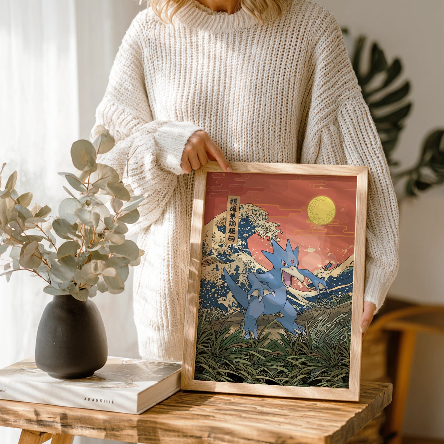 Person holding a framed artwork of Golduck Pokemon in a natural setting