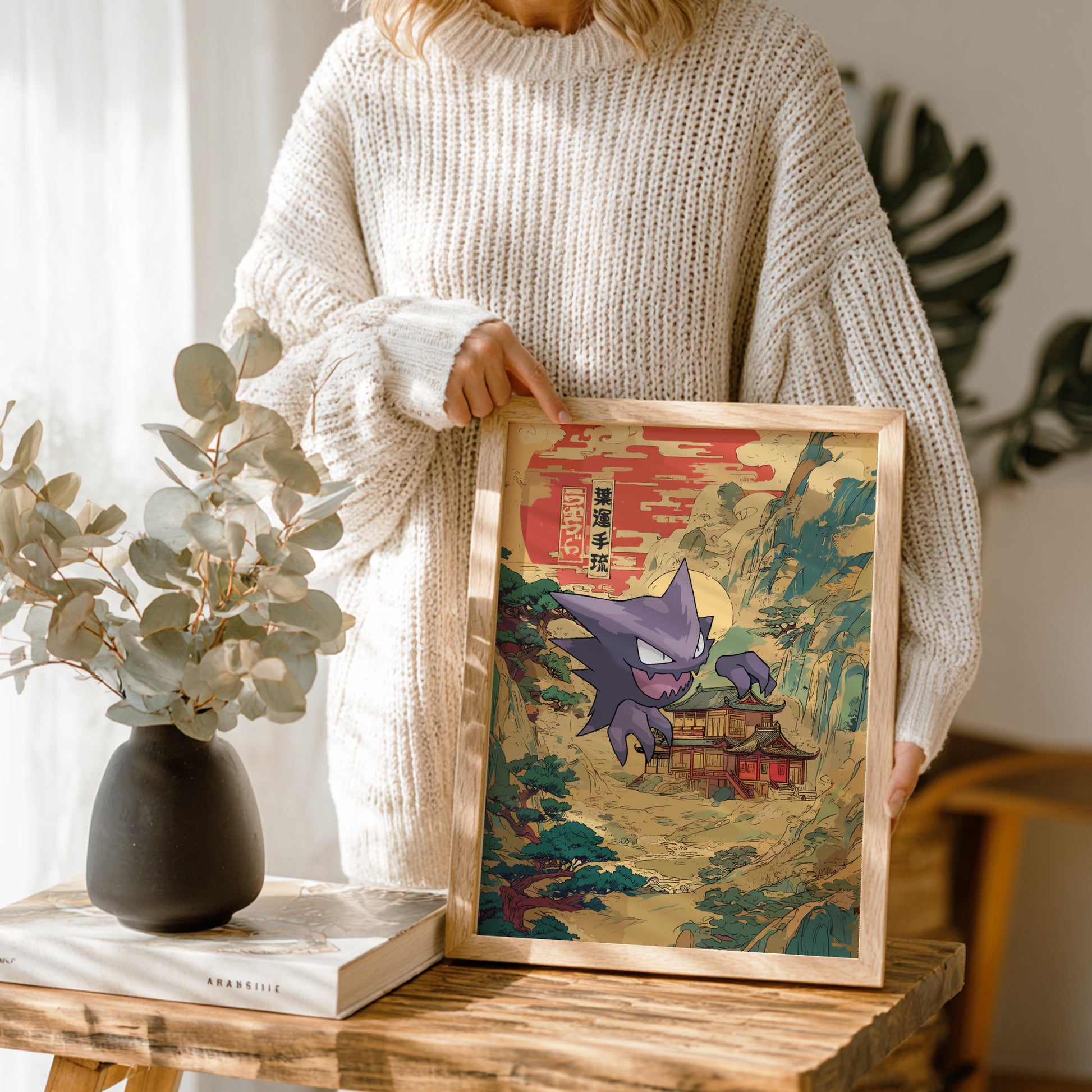 Person holding a framed artwork of Haunter Pokemon character in a traditional Japanese setting