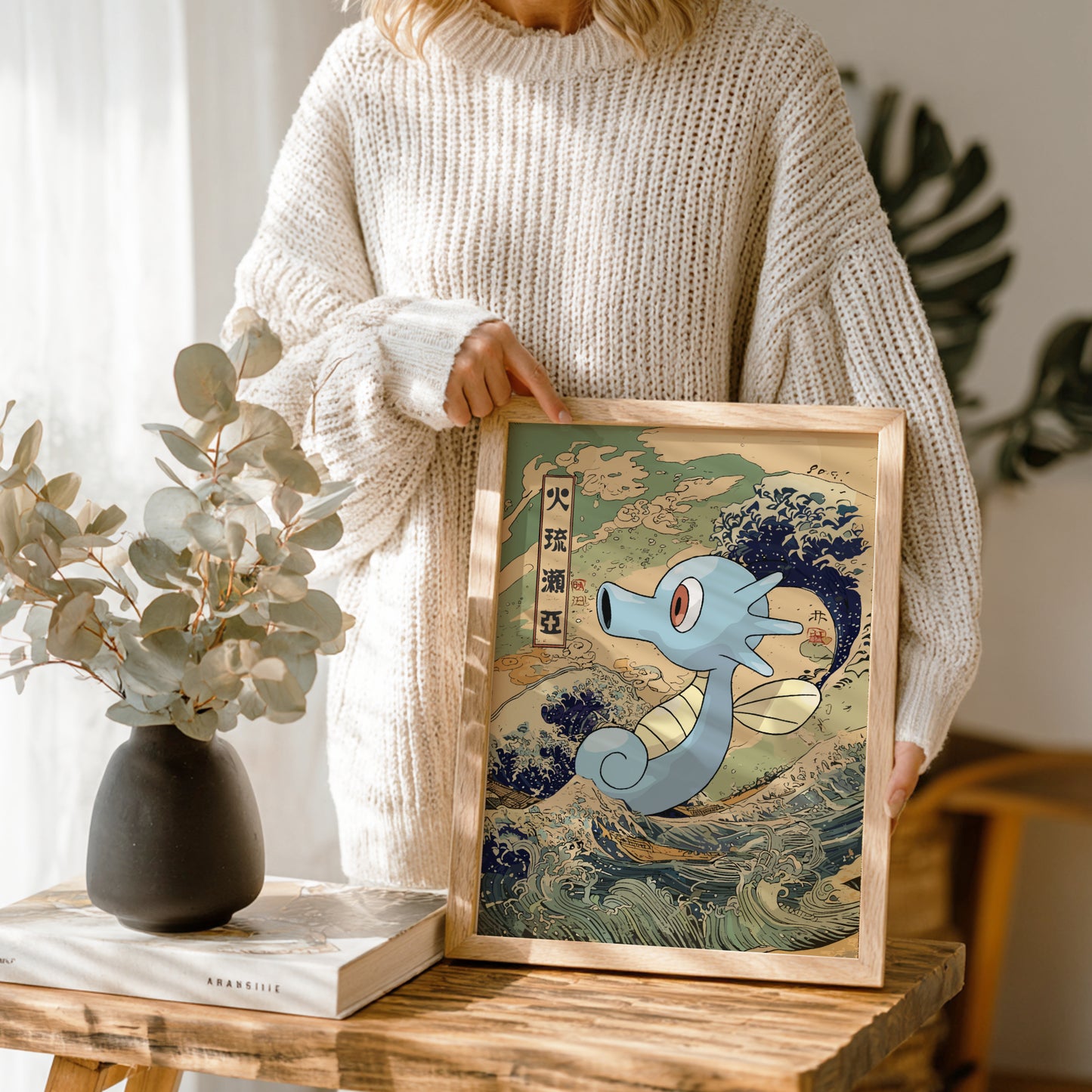 Person holding a framed artwork of Horsea Pokemon with a wave background