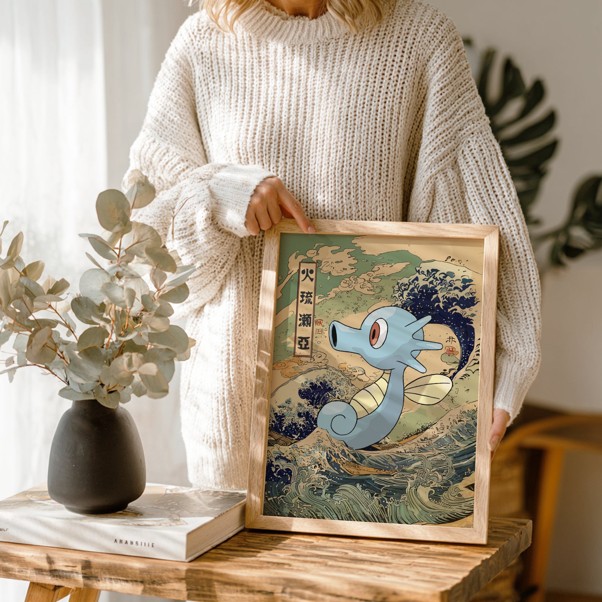 Person holding a framed artwork of Horsea Pokemon with a wave background