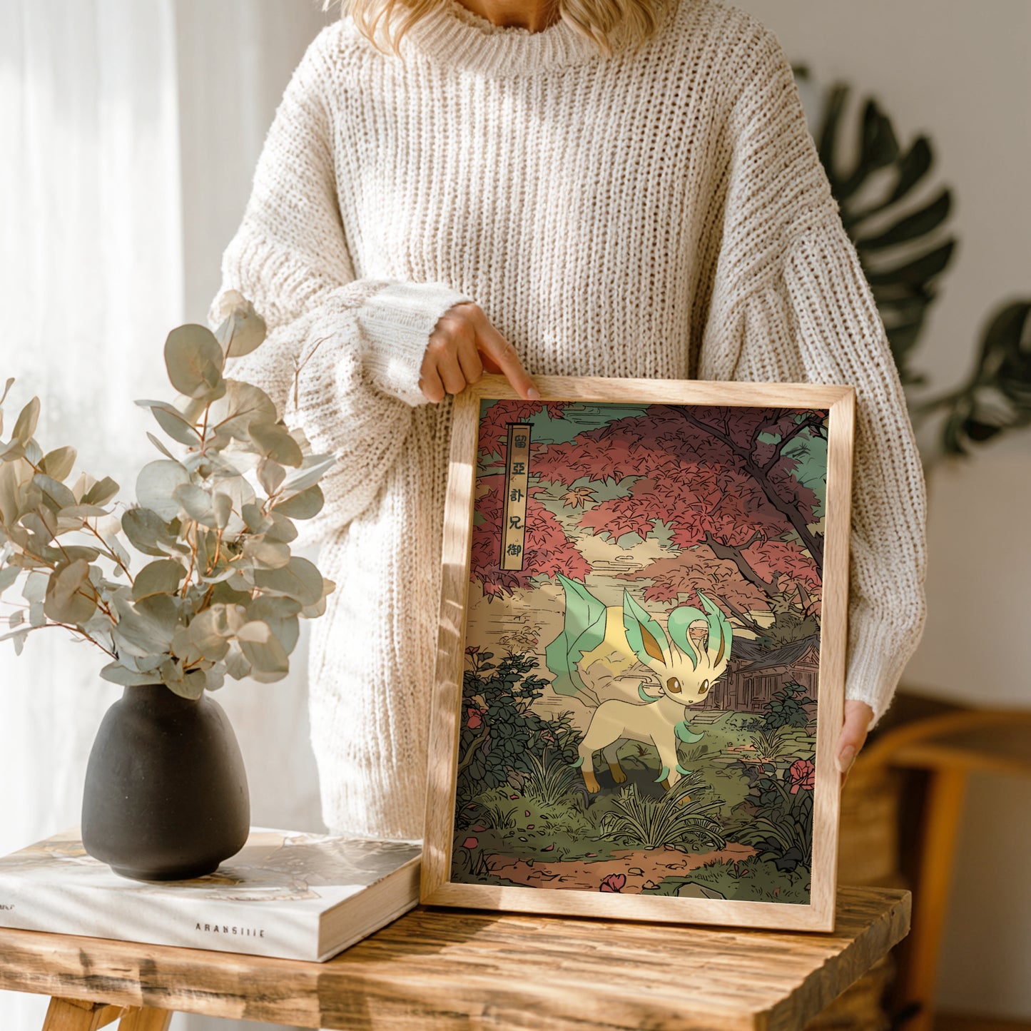 Person holding a framed artwork of Leafeon Pokemon in a natural setting