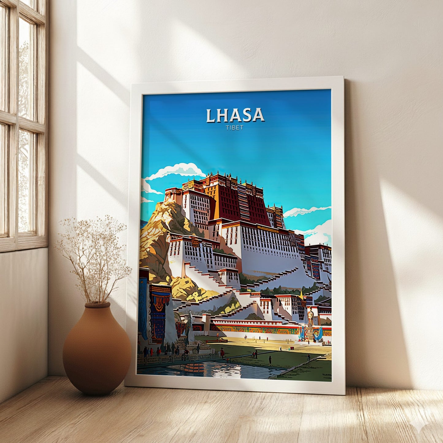Framed poster of Lhasa, Tibet on a wall in a bright room with a vase on the floor.