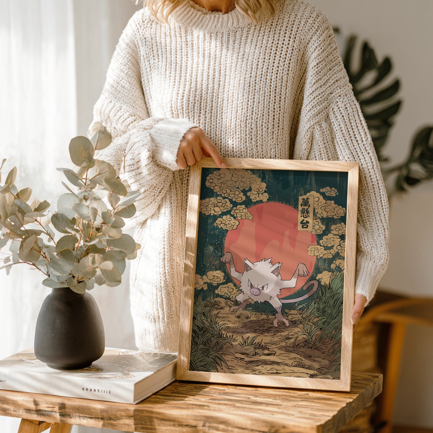 Person holding a framed artwork of Mankey Pokemon in a natural setting