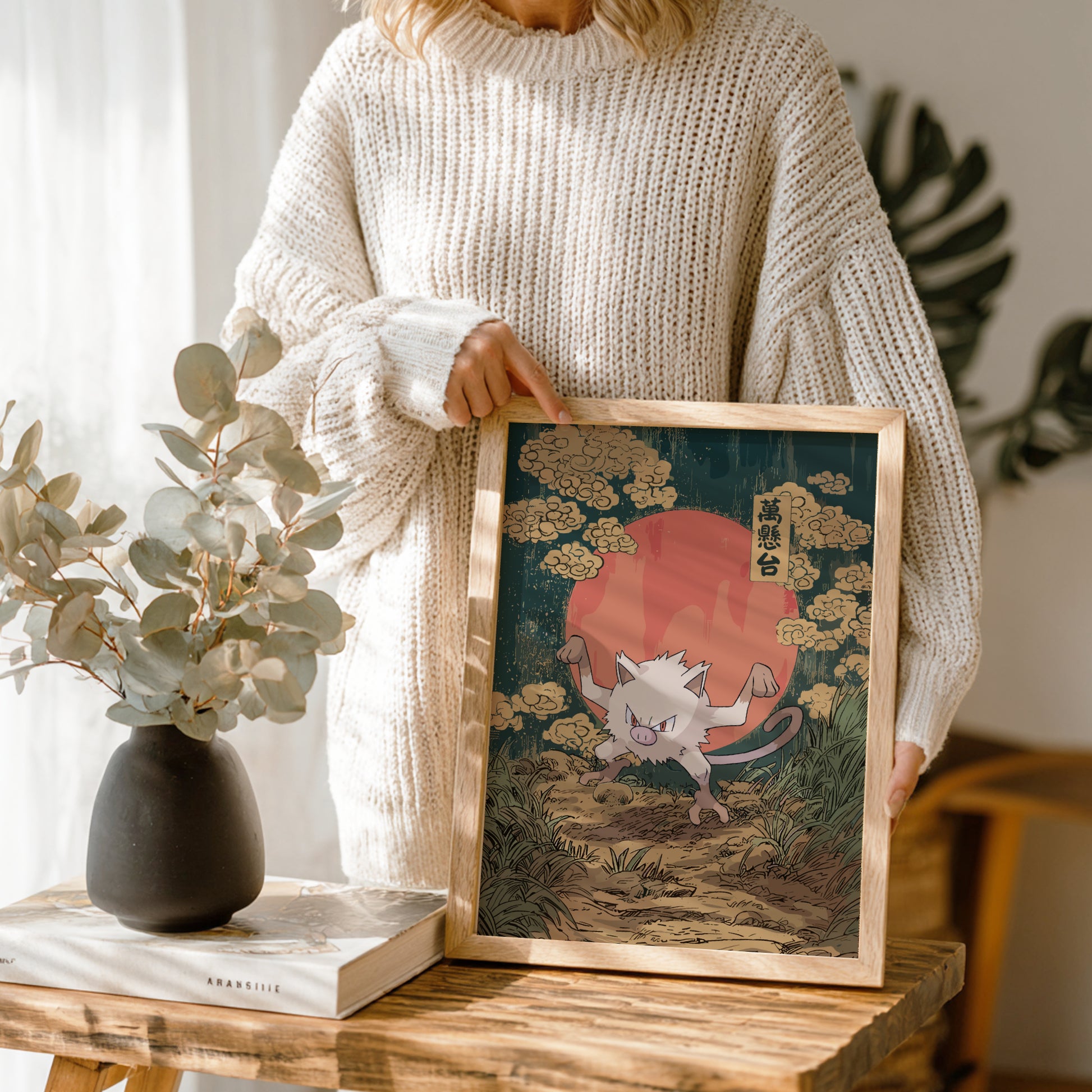 Person holding a framed artwork of Mankey Pokemon in a natural setting