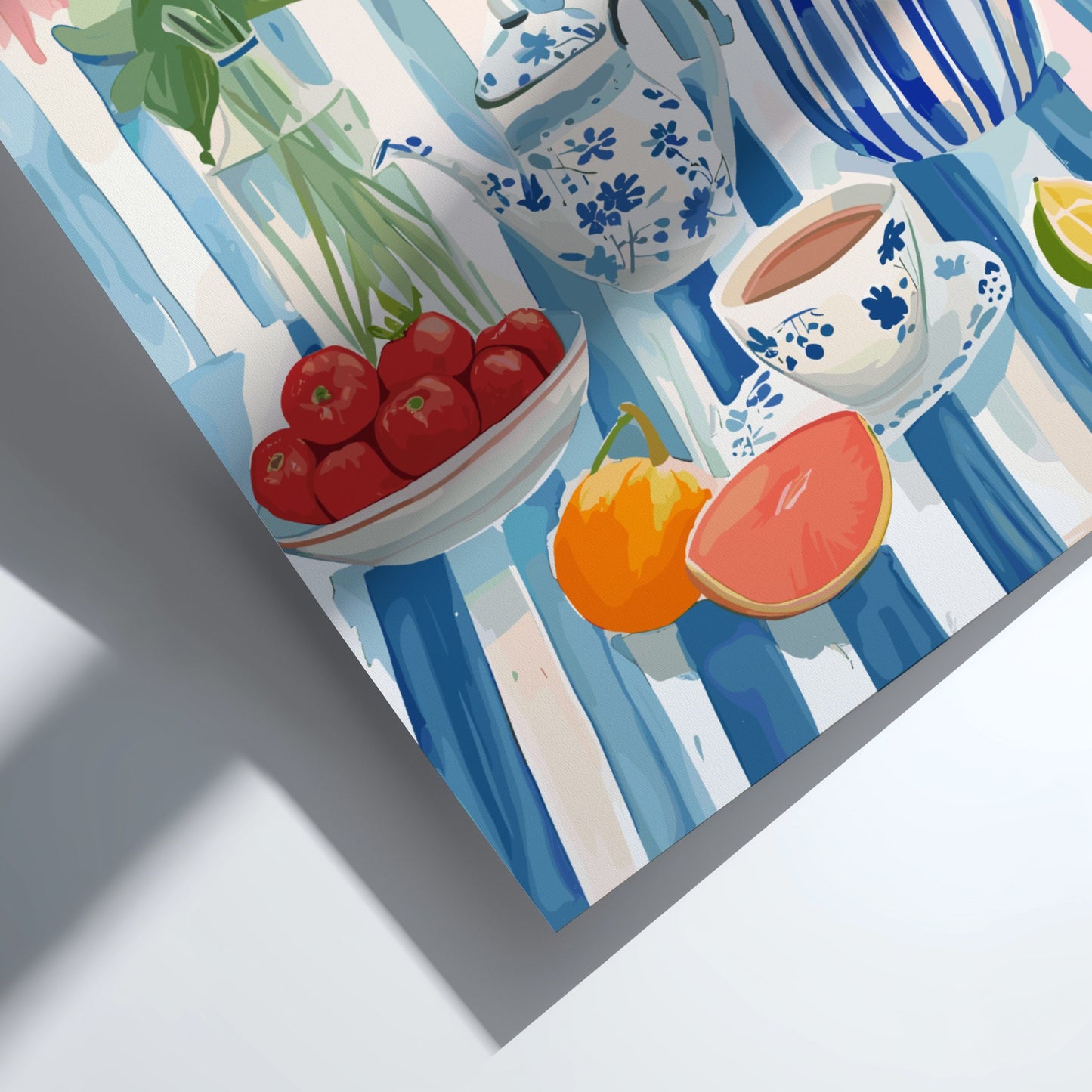 Table setting with teapot, cups, and fruits on a blue and white striped tablecloth.