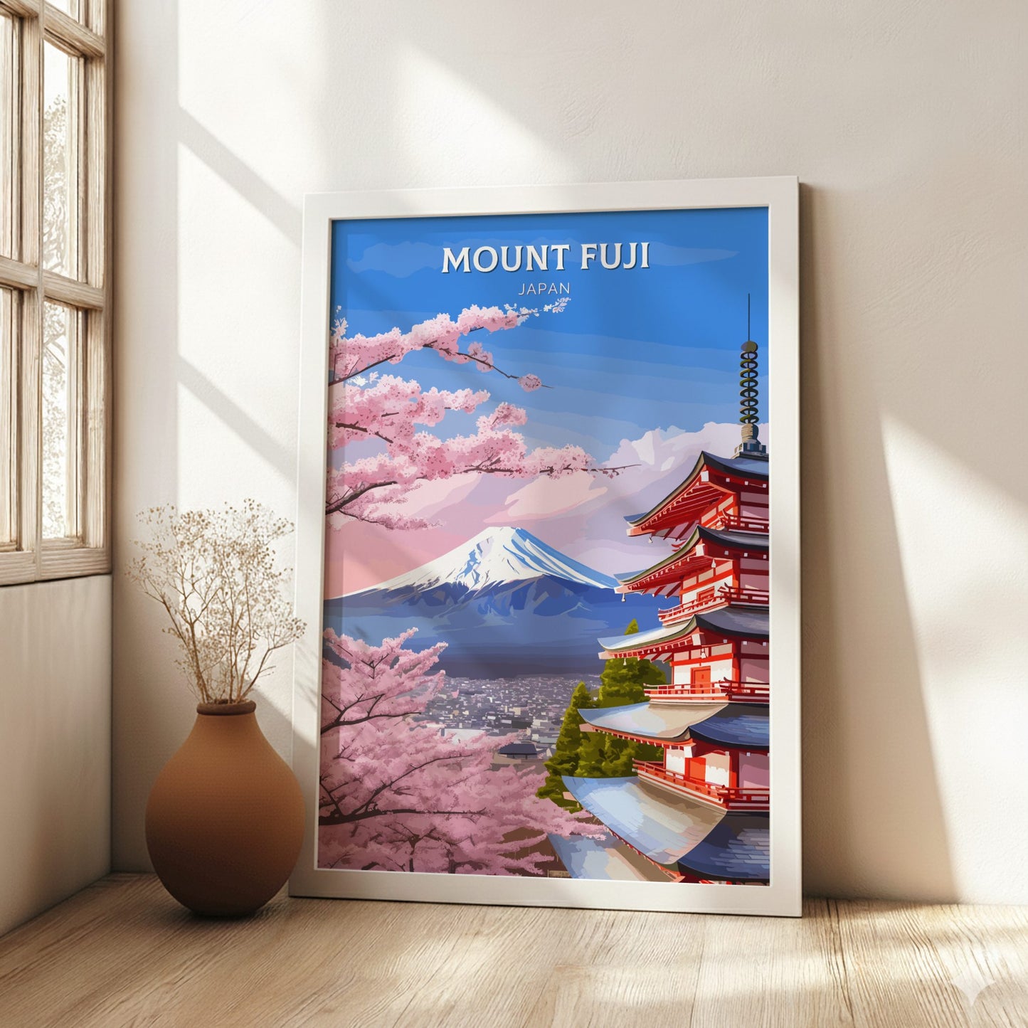 Framed poster of Mount Fuji and cherry blossoms in a room with a vase on a wooden floor.