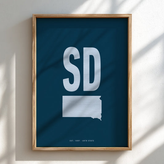 Framed poster with 'SD' and outline of South Dakota on a blue background