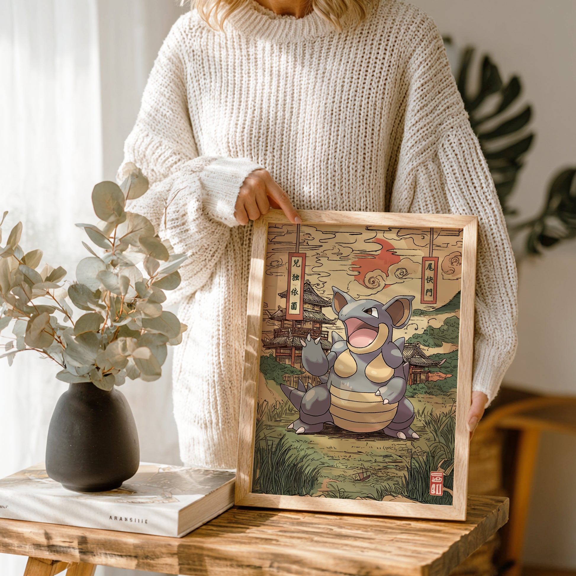 Person holding a framed illustration of a stylized Nidoqueen Pokemon in a traditional Japanese setting.