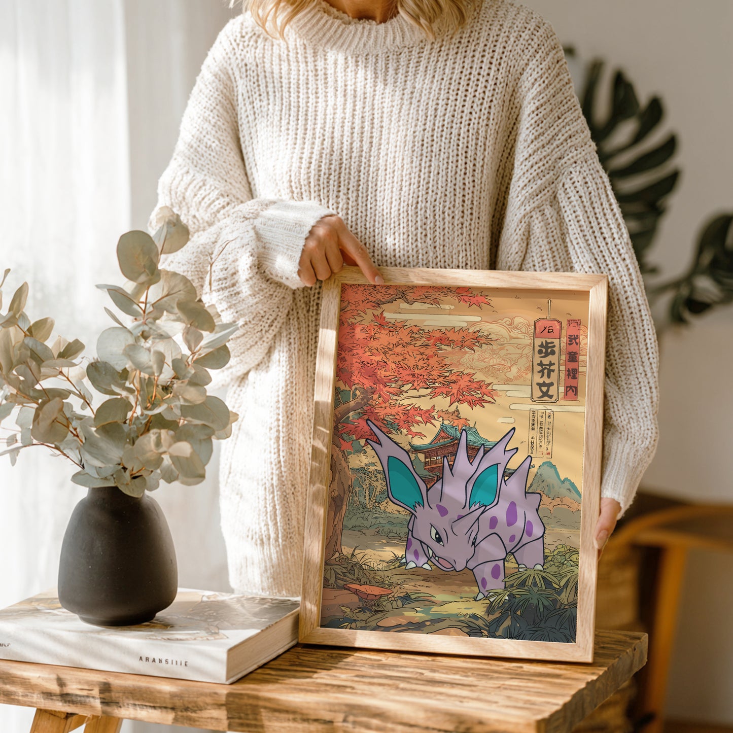 Person holding a framed illustration of Nidorino Pokemon in a natural setting