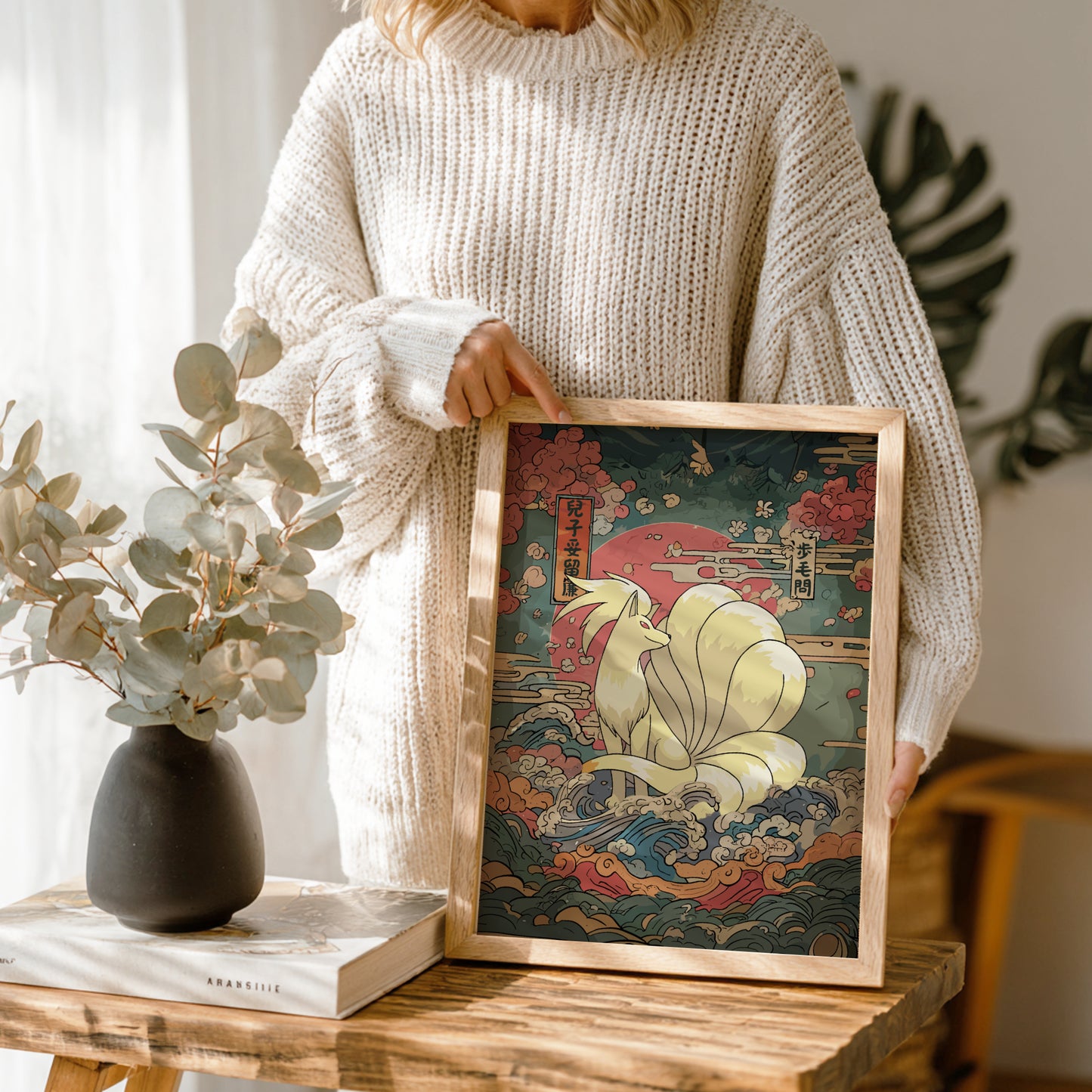 Person holding a framed artwork of Ninetales Pokemon in a home setting