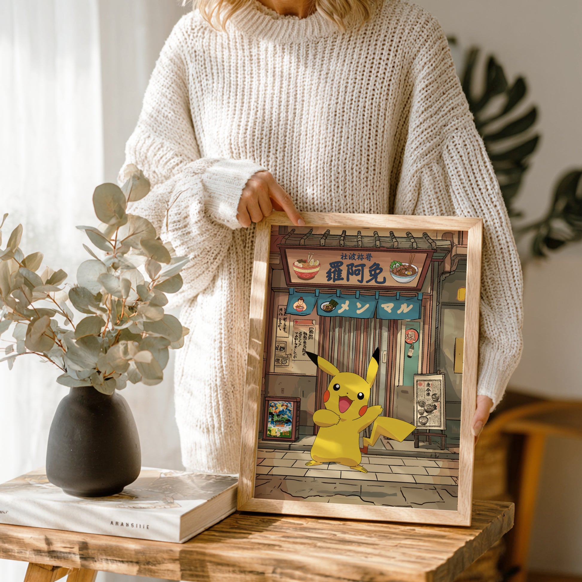 Person holding a framed picture of Pikachu in a store setting on a wooden table.