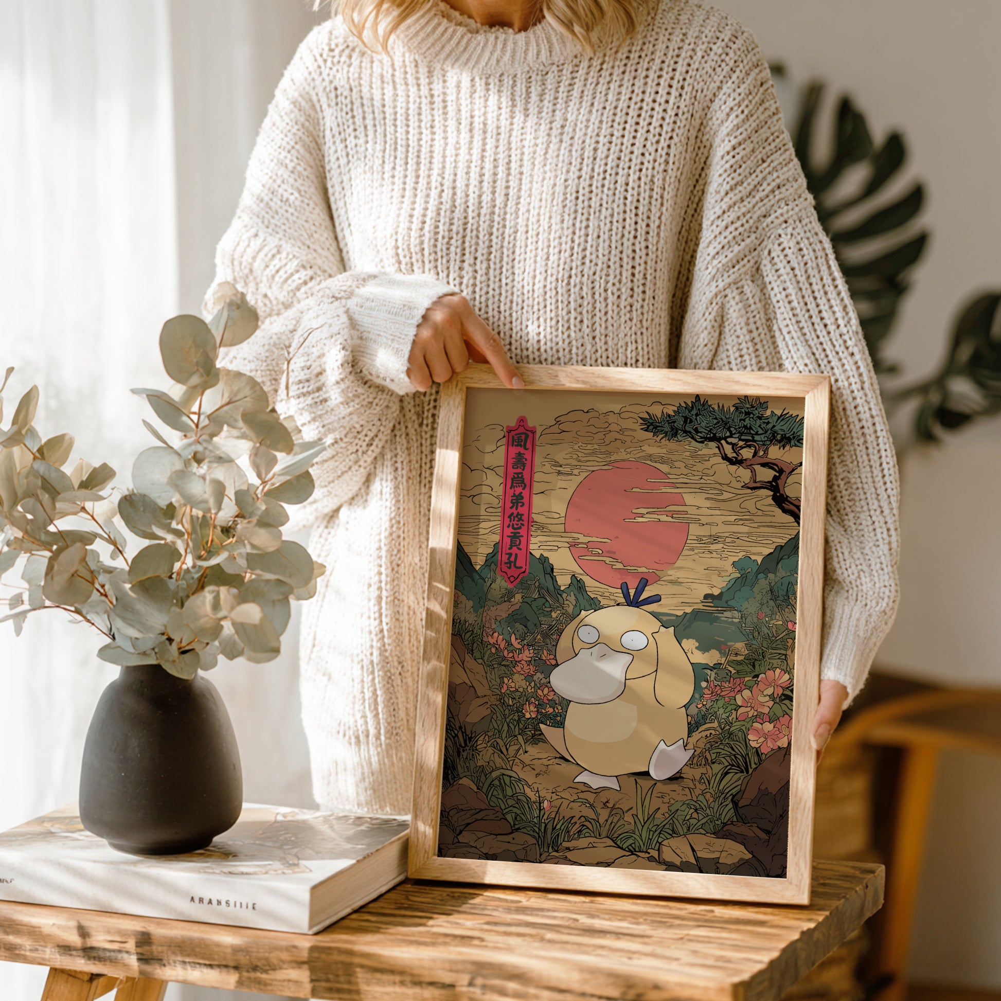 Person holding a framed artwork of Psyduck Pokémon character with a scenic background