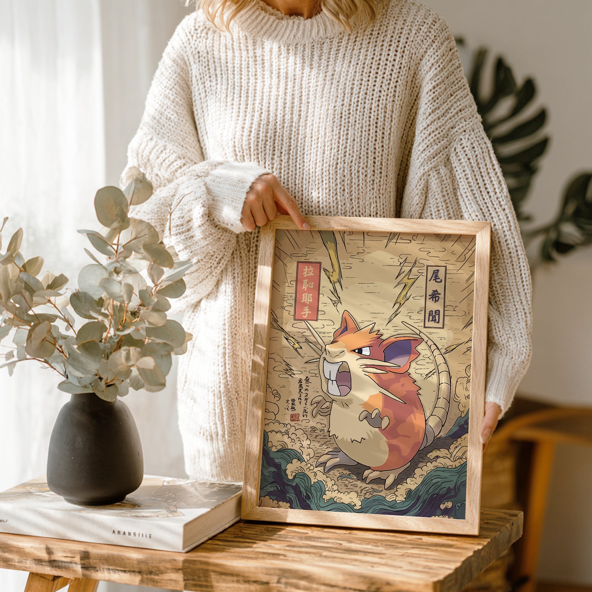 Person holding a framed artwork of Raticate Pokemon in a traditional style, with a vase and plant in the background.