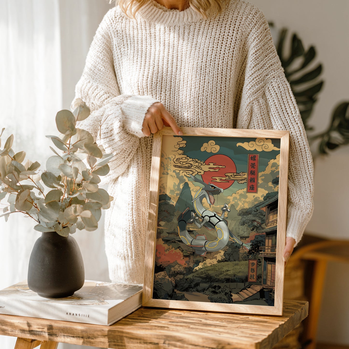 Person holding a framed artwork with a Rayquaza Pokemon design in a home setting