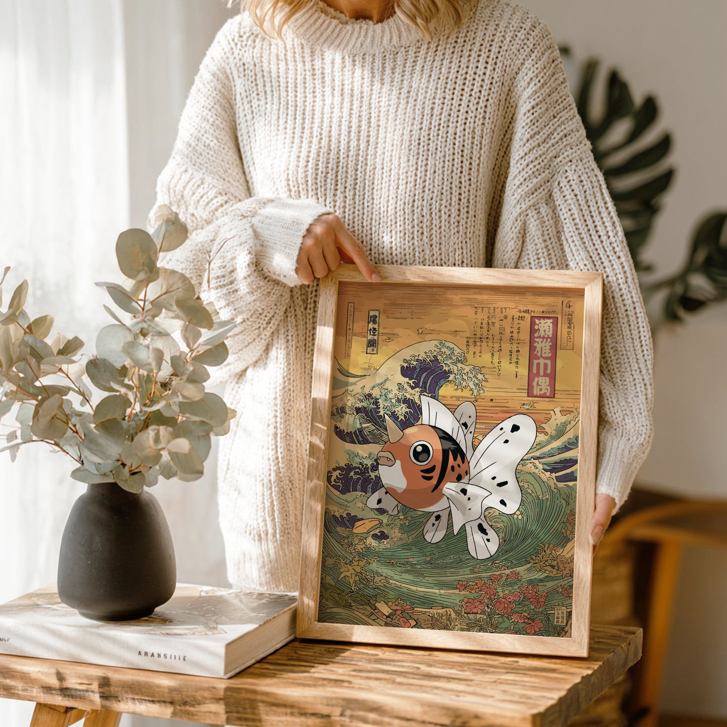 Person holding a framed artwork of Seaking Pokemon on a wooden table.