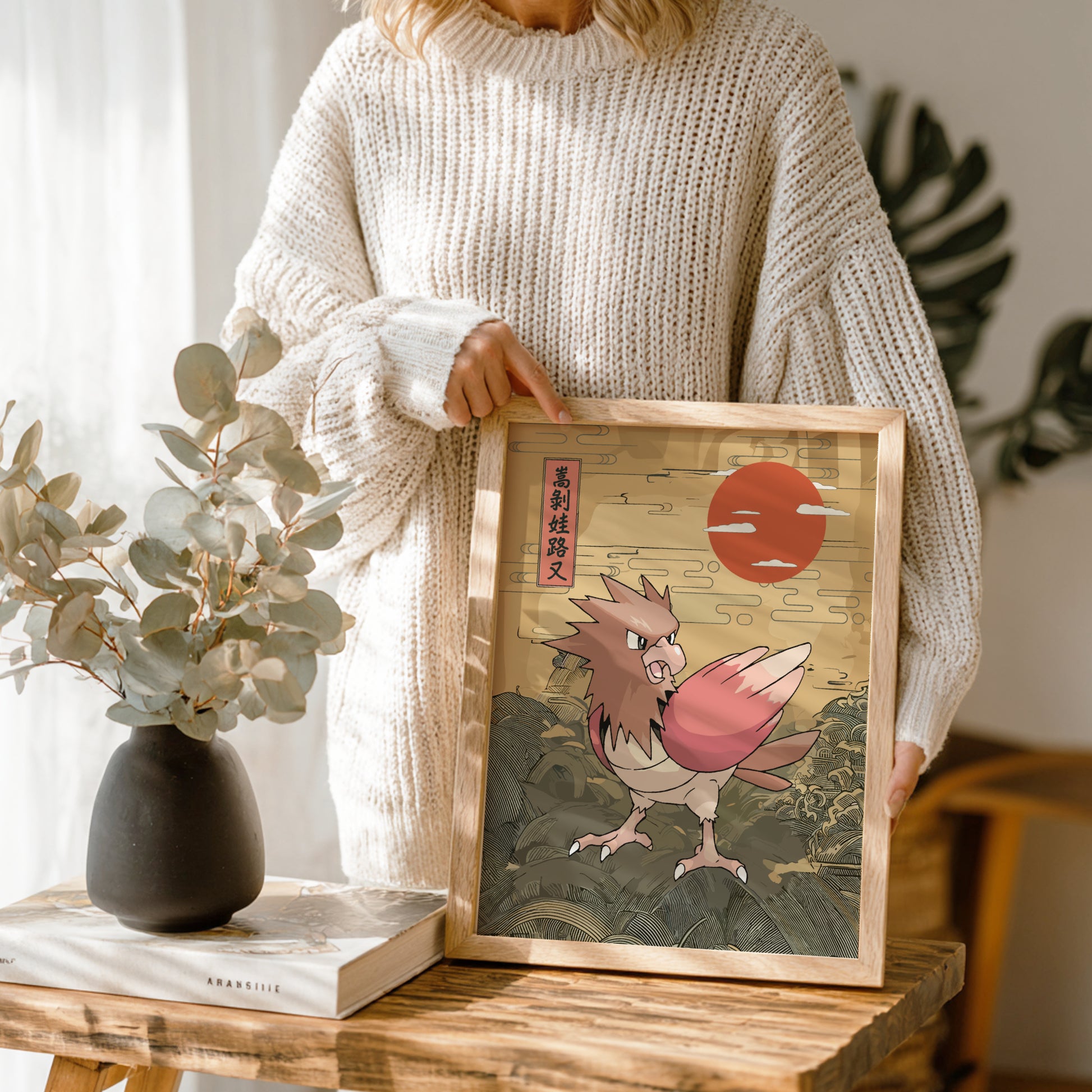 Person holding a framed artwork of Spearow Pokemon with a red sun in the background