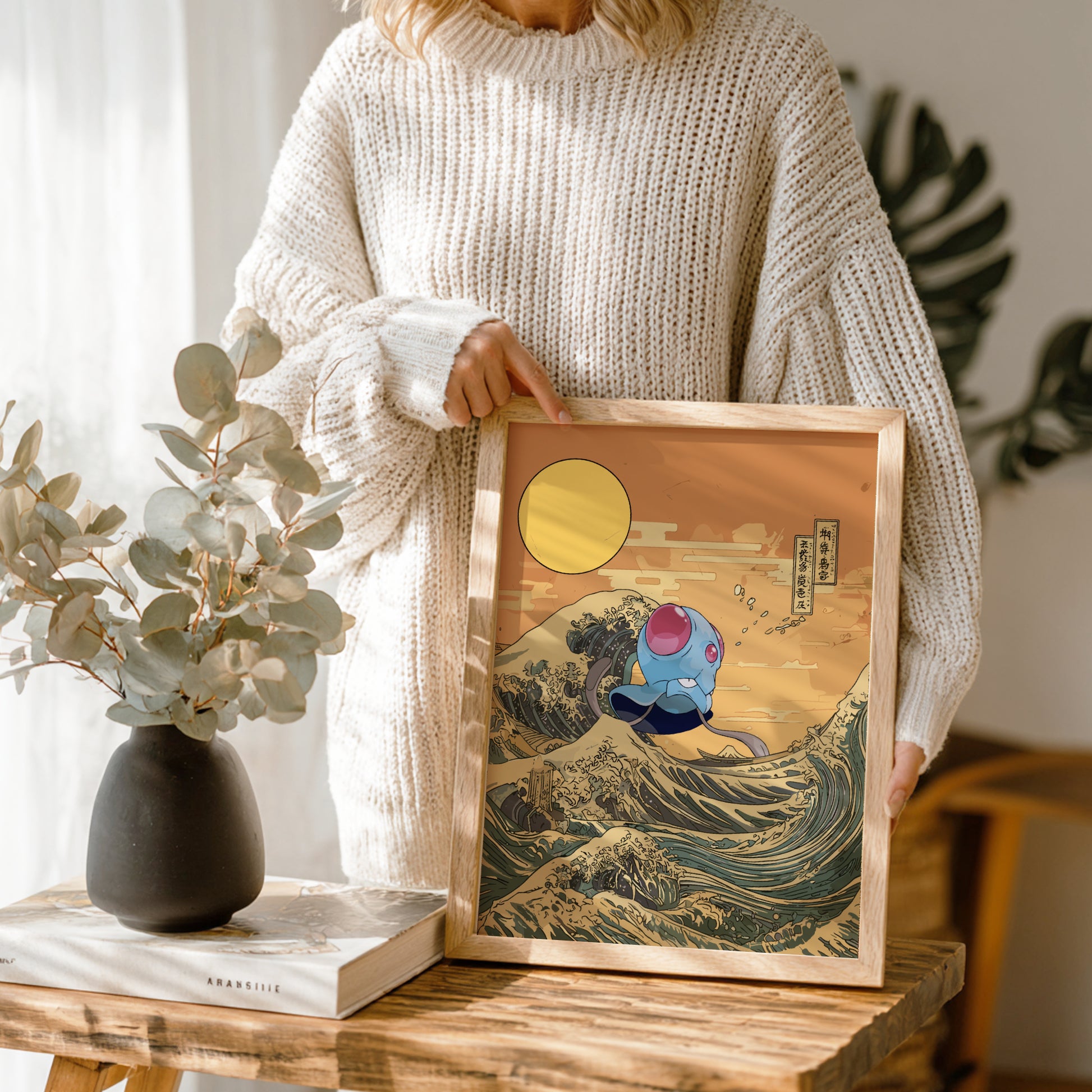 Person holding a framed artwork with Tentacool Pokemon character on a wave, similar to 'The Great Wave off Kanagawa'.