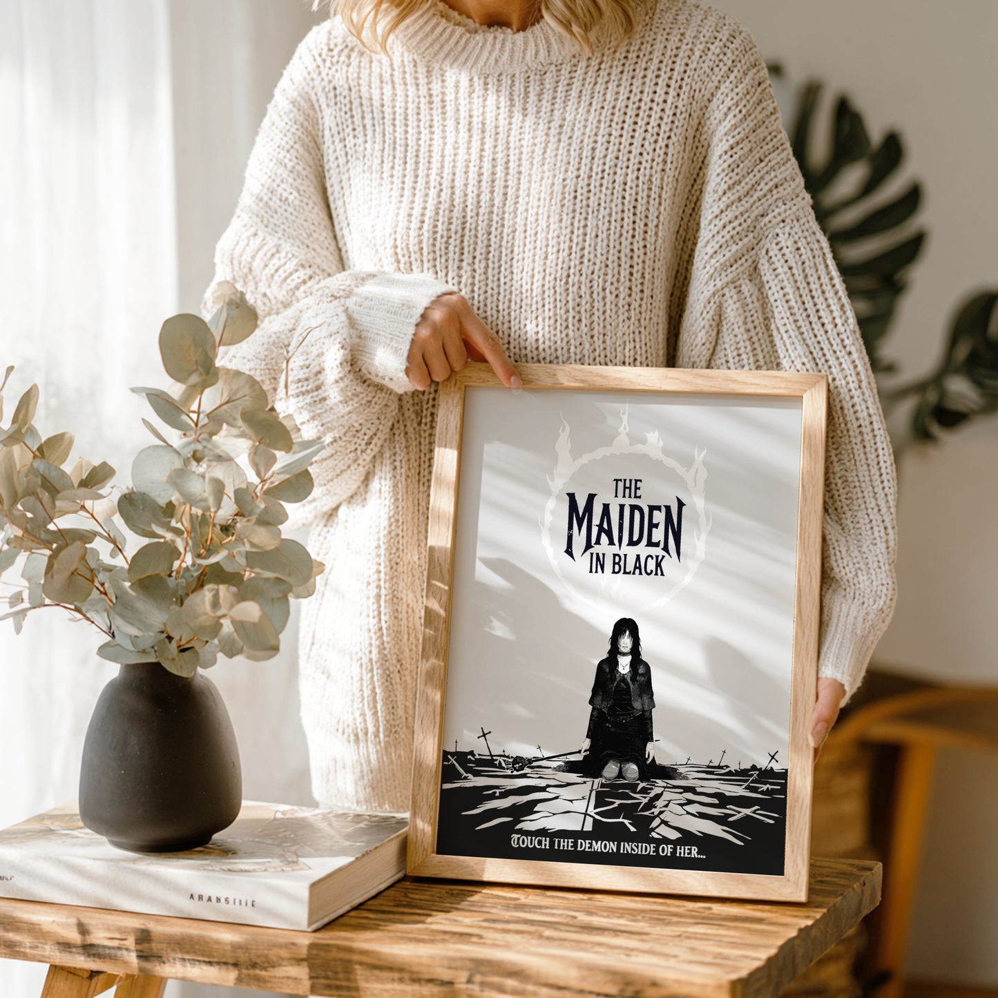 Person holding a framed artwork of The Maiden in Black from Dark Souls on a wooden table.
