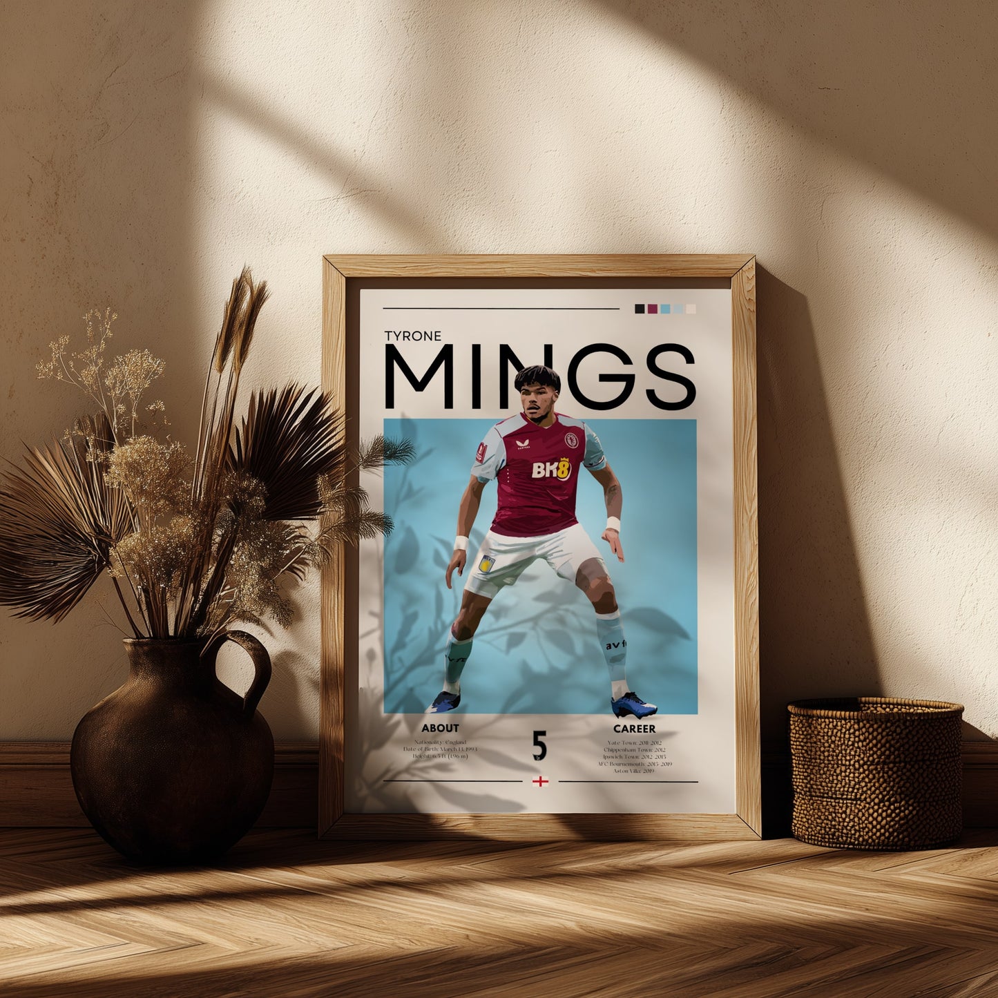 Framed poster of a soccer player with 'Tyrone Mings' on a wooden shelf.