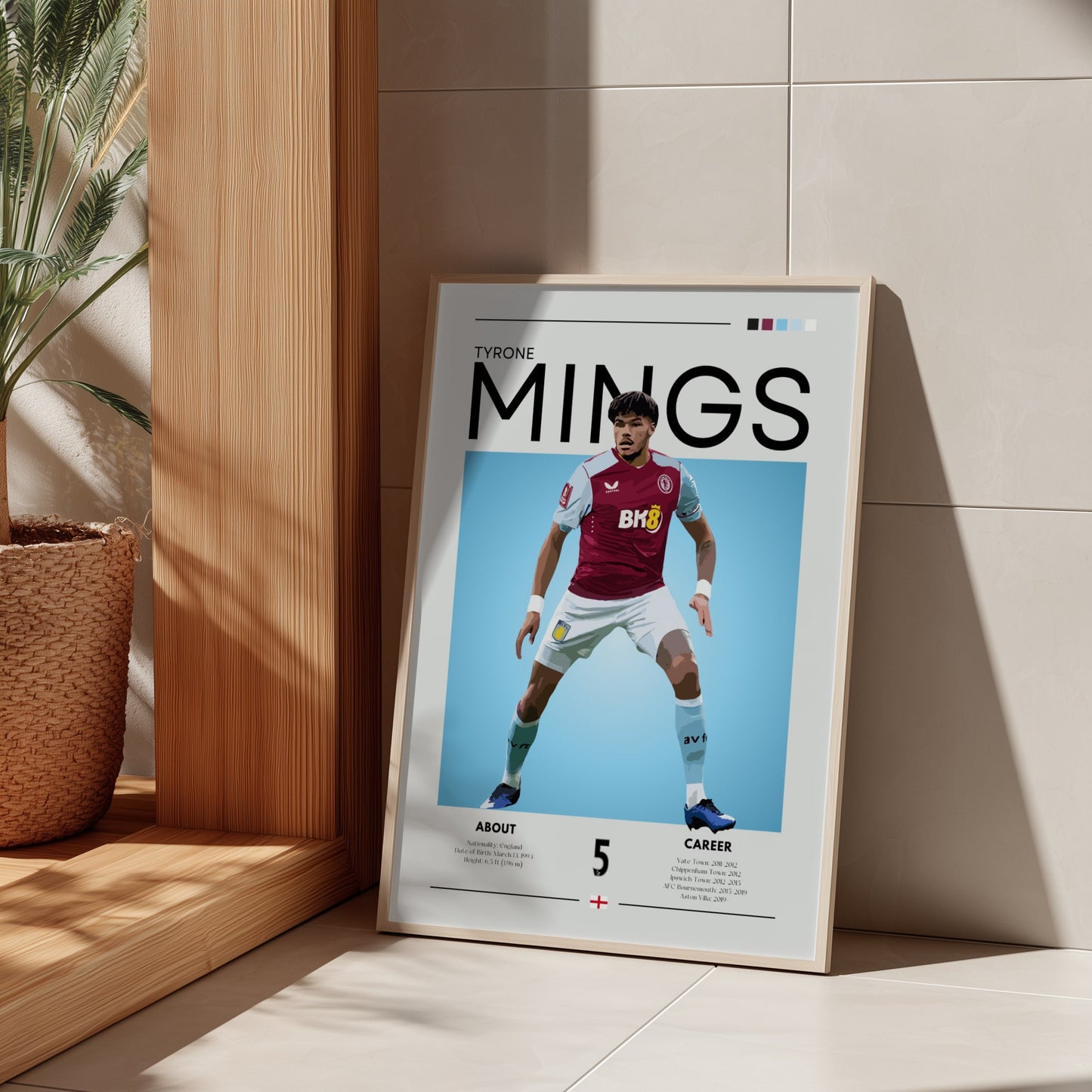 Framed poster of a soccer player named Mings on a light-colored wall.