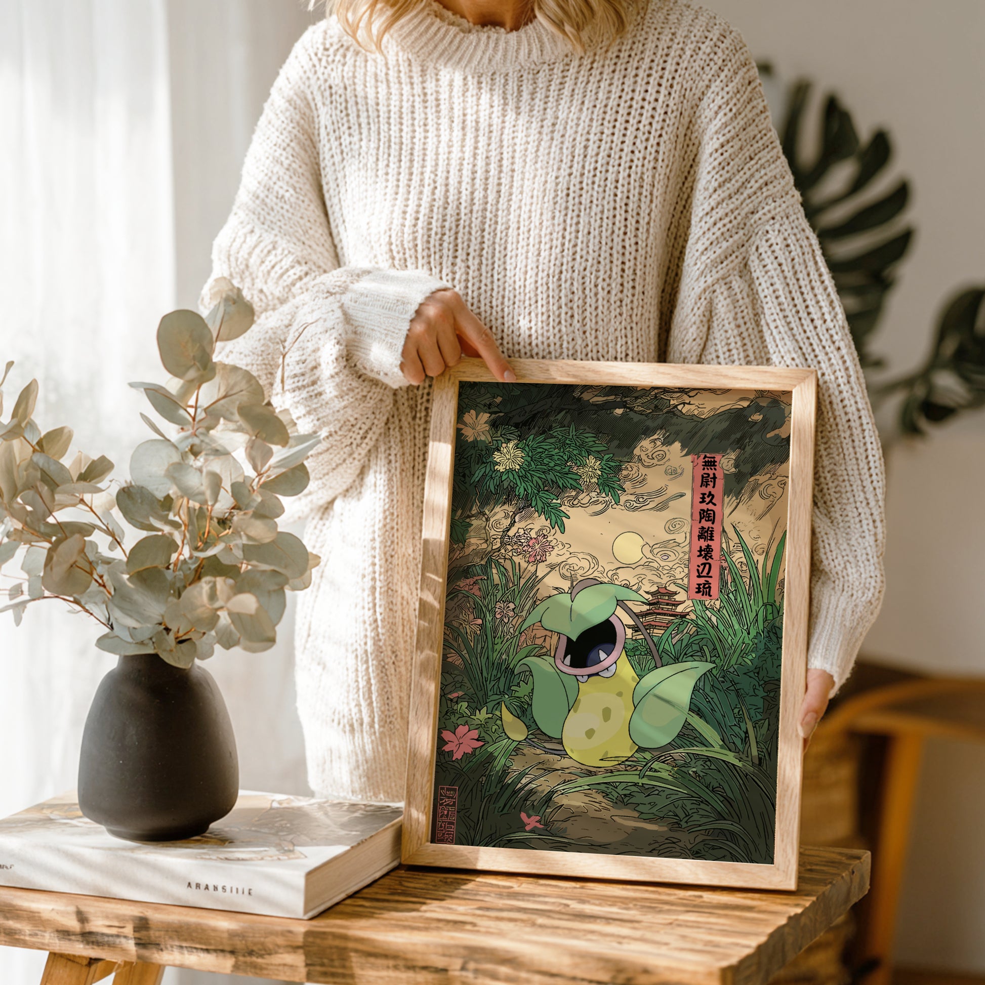 Person holding a framed artwork of Victreebel Pokemon in a natural setting