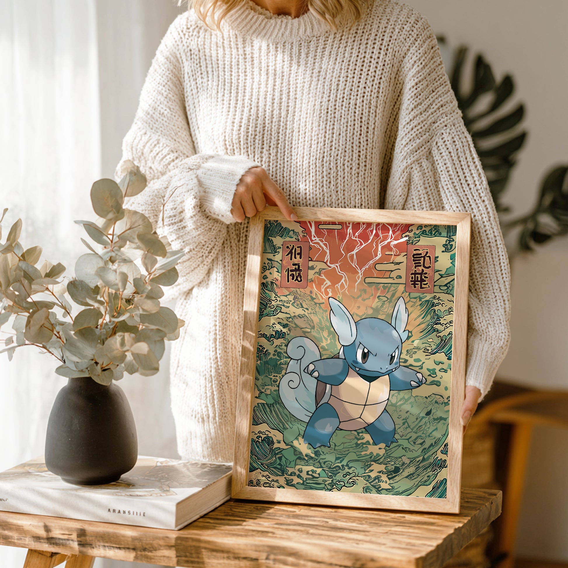 Person holding a framed illustration of Wartortle Pokemon character on a wooden table with plants in the background