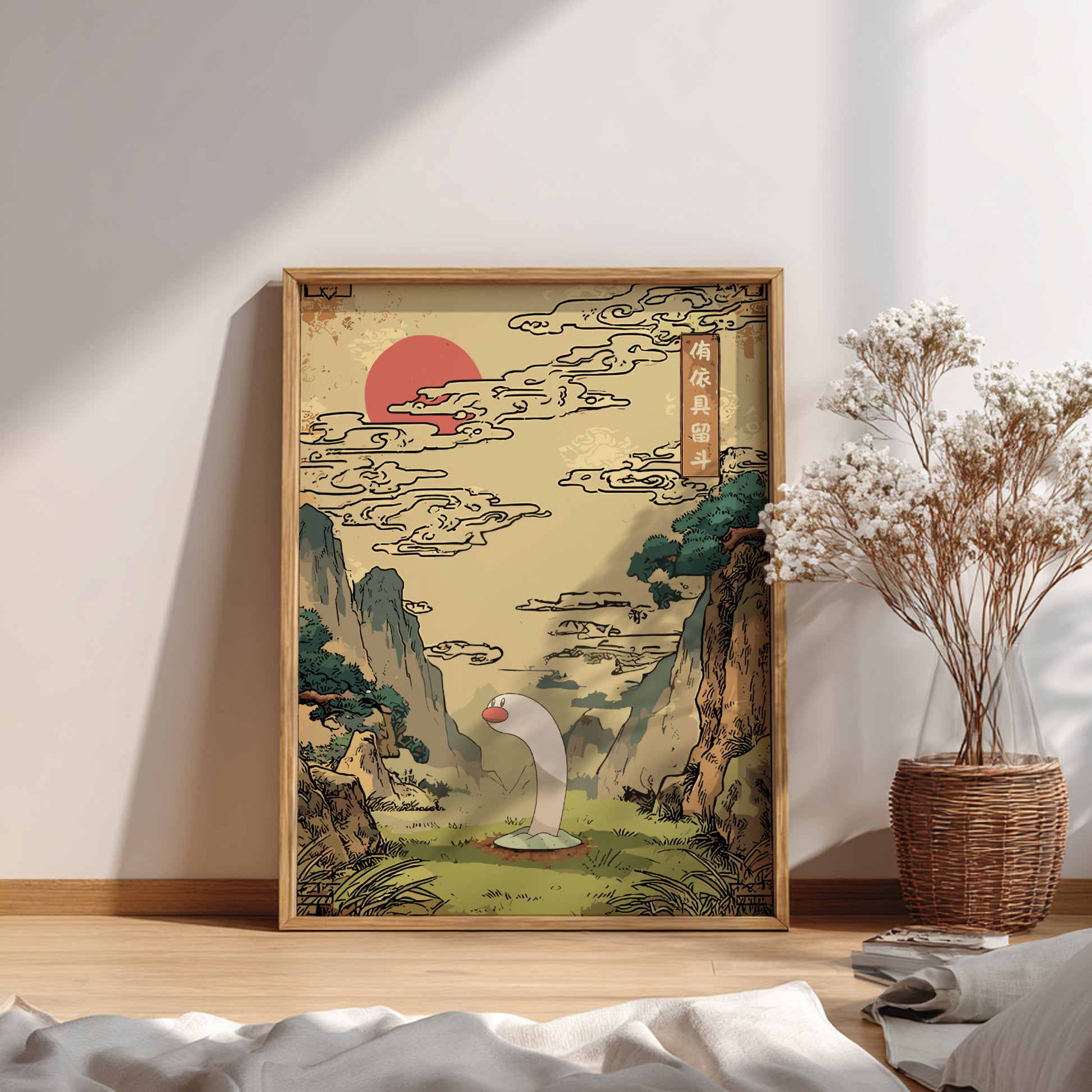 Framed artwork of Wiglett Pokemon and a traditional landscape with a mountain and sun, placed on a wooden floor.
