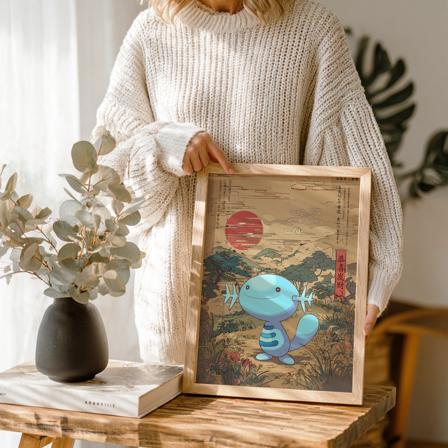 Person holding a framed artwork with Wooper Pokemon in a natural setting