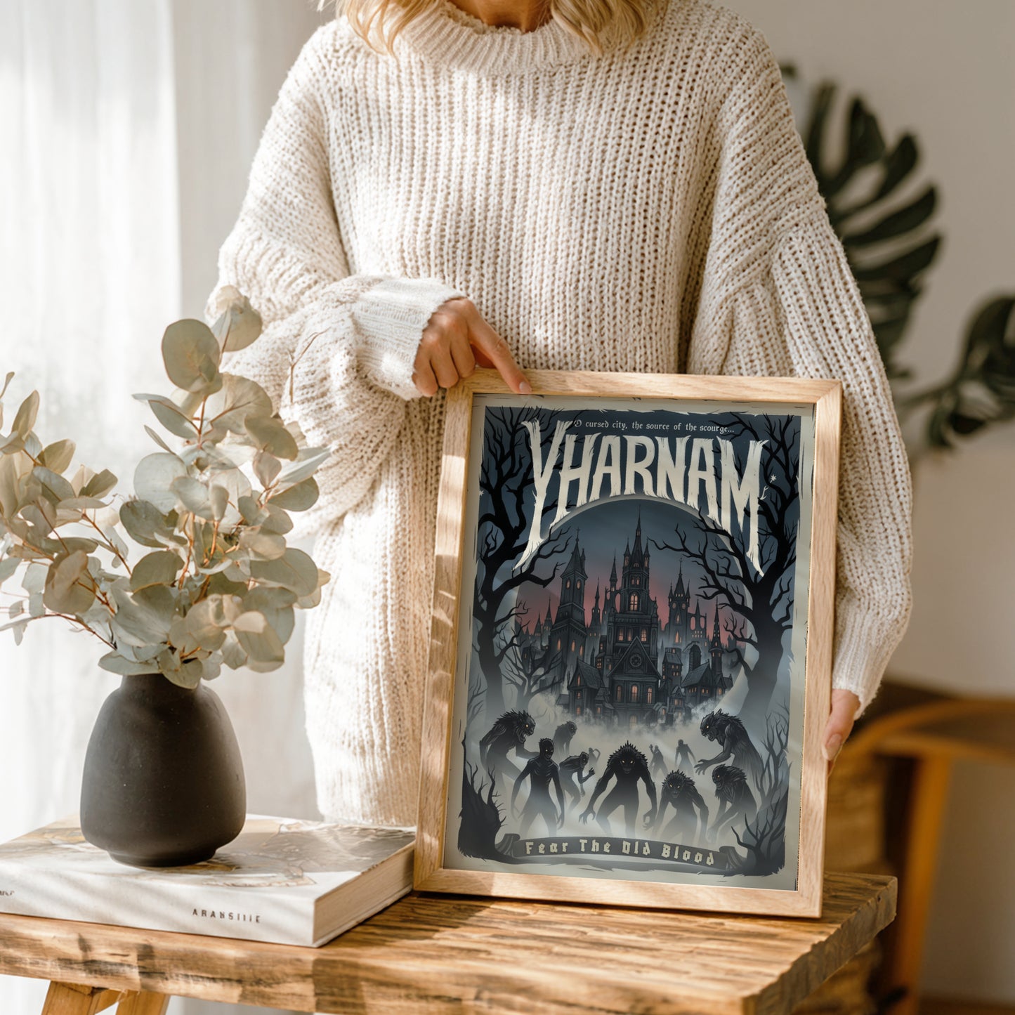 Person holding a framed print titled 'Yharnam' in a cozy indoor setting.