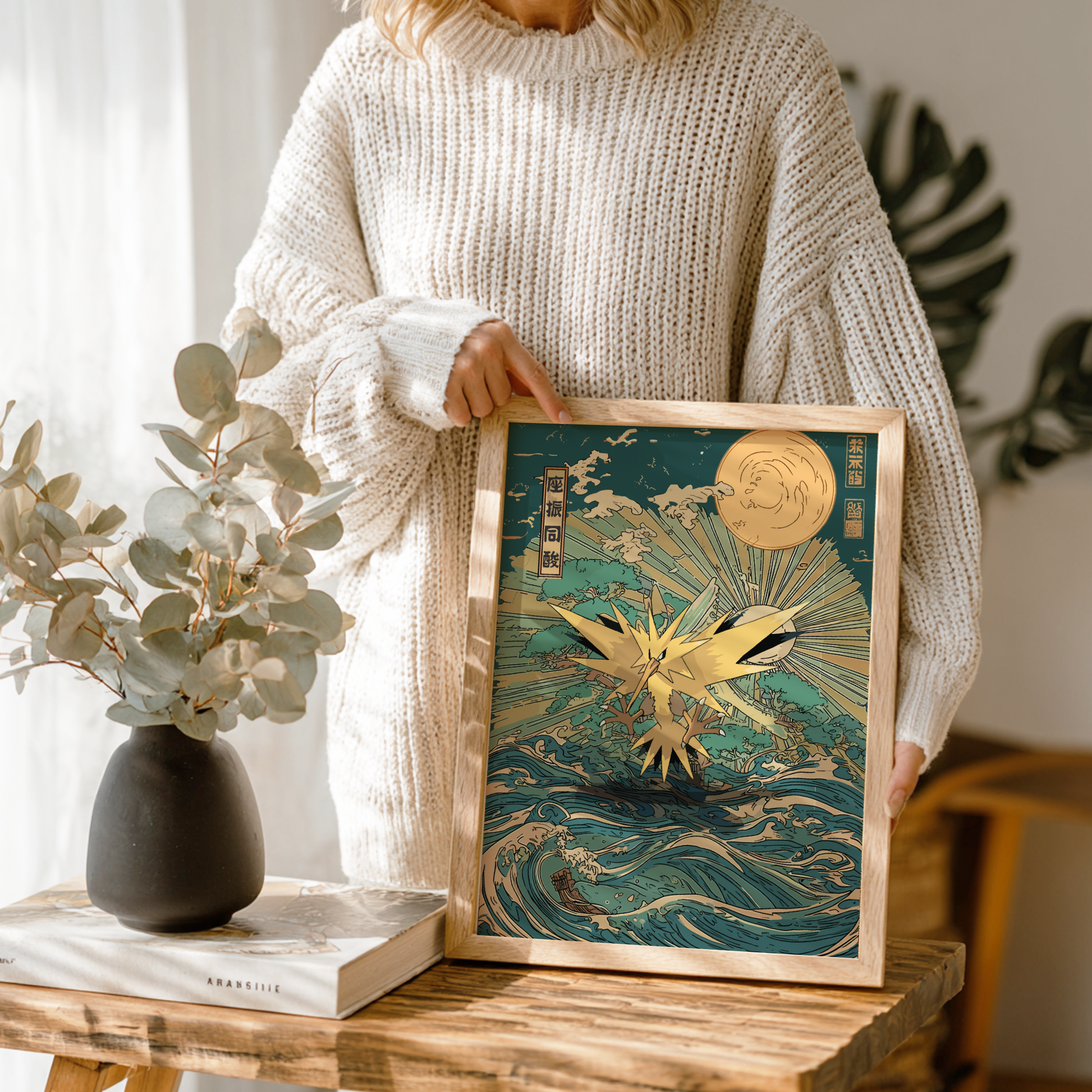Person holding a framed artwork with a Zapdos Pokemon design in a home setting