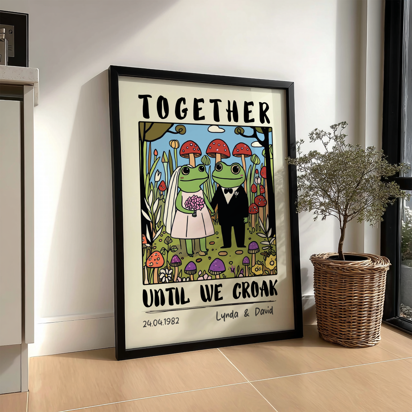 Framed artwork with frogs in wedding attire and text 'Together until we croak' on a wall.
