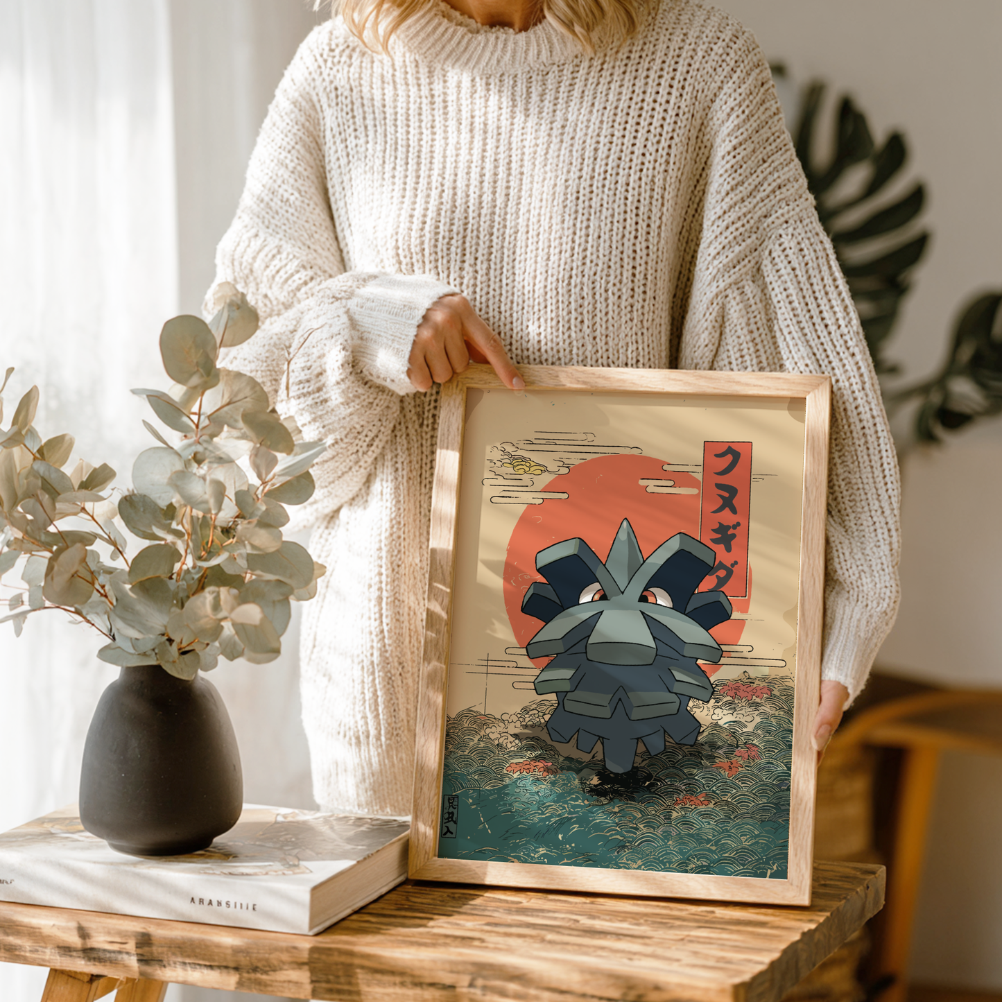 Person holding a framed artwork of Pineco Pokemon with a red sun in the background.