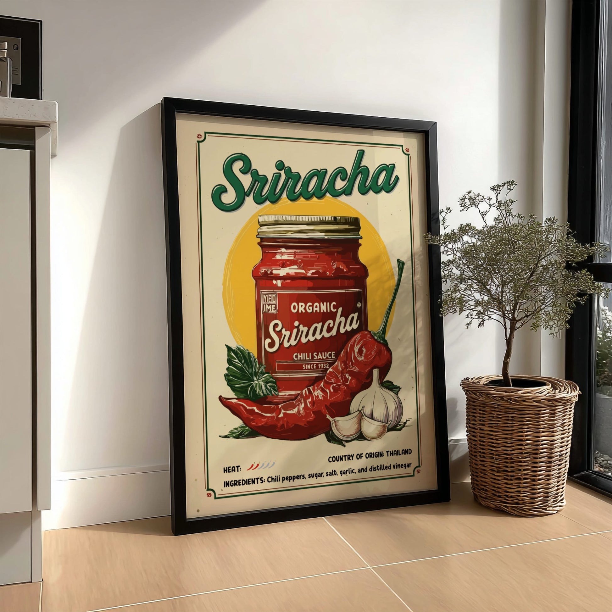 Framed Sriracha sauce poster on a wall with a plant and basket below.