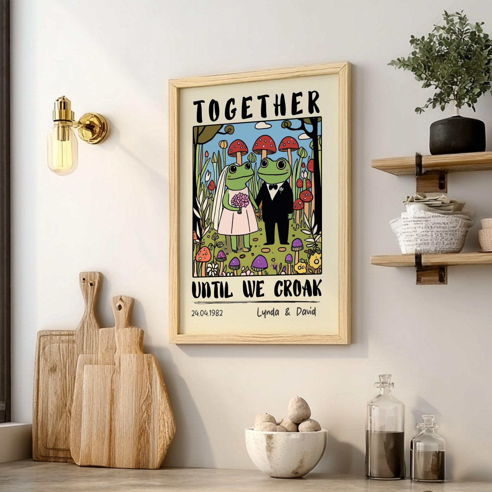 Framed artwork with cartoon frogs and text 'Together Until We Croak' on a wall with decor items below.