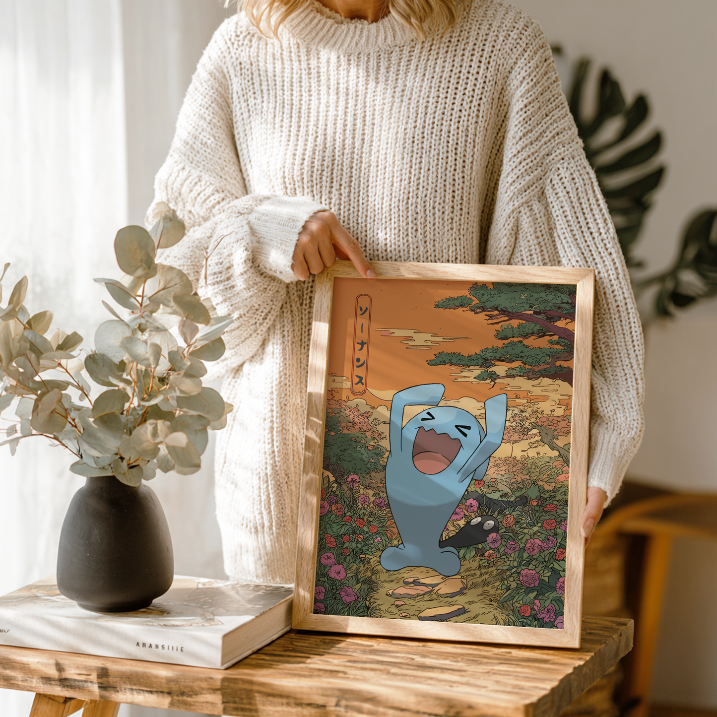 Person holding a framed artwork with Wobbuffet Pokemon character in a scenic setting